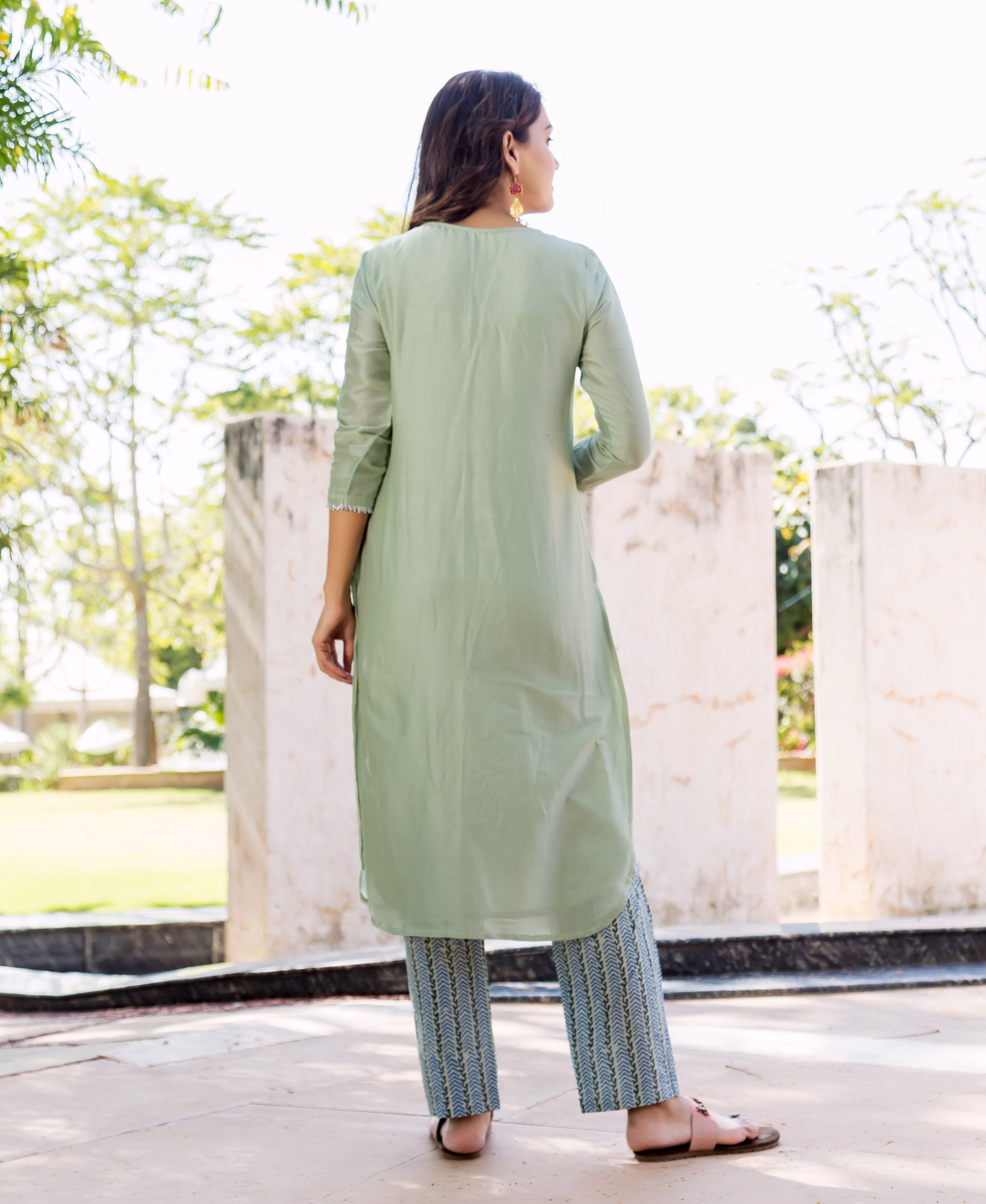 Rear view of model wearing pistachio green kurta and blue hand-block printed pants.