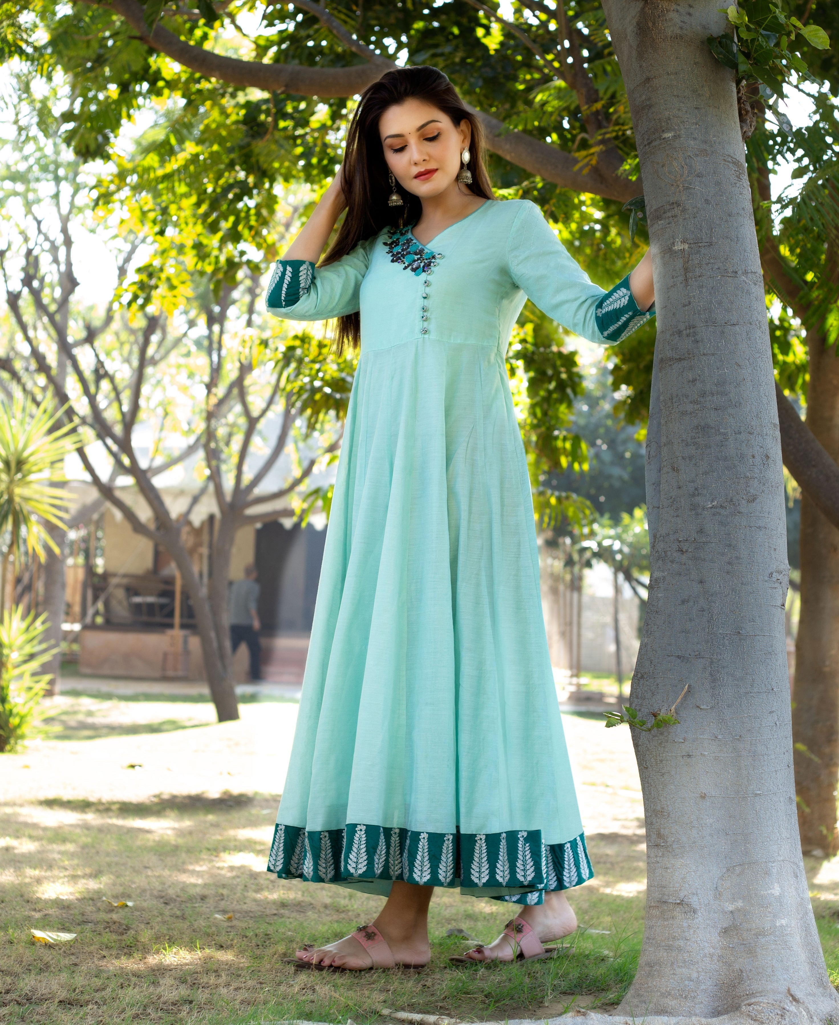 Model in mint green Angrakha dress with embroidered neck and dark green leaf block print.