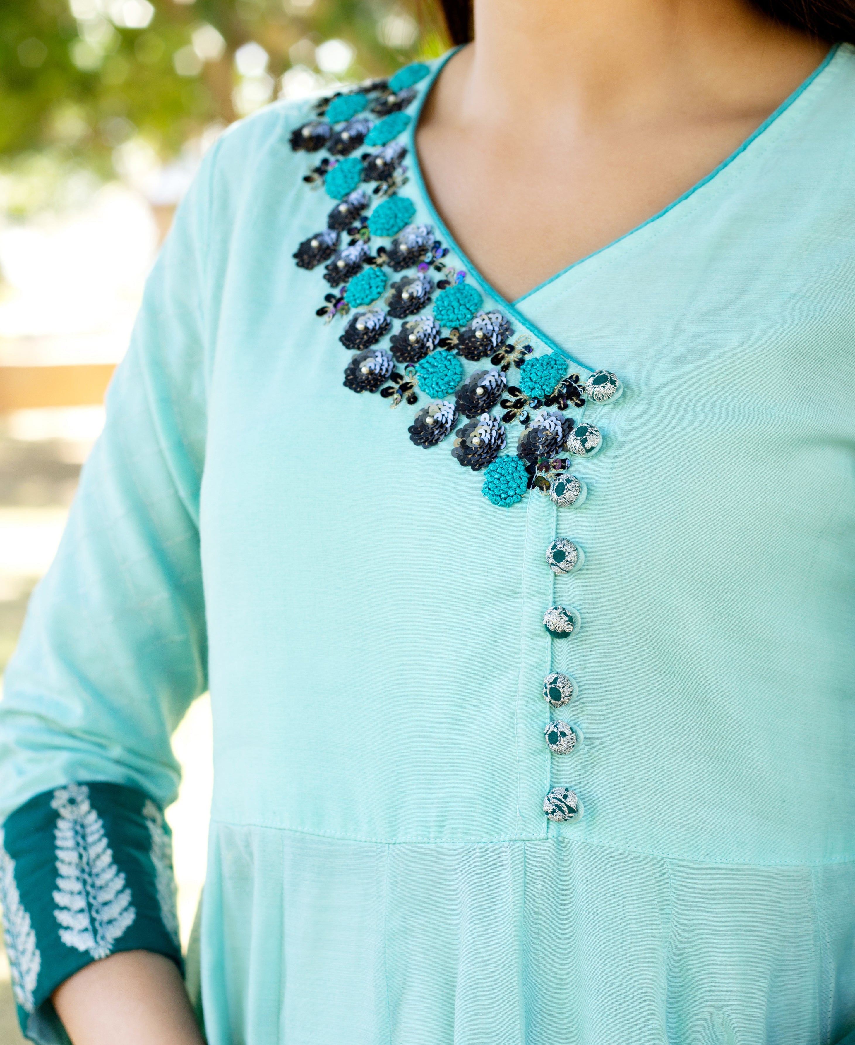 Mint green Angrakha dress with teal and black floral embroidery, decorative buttons, and printed cuff.
