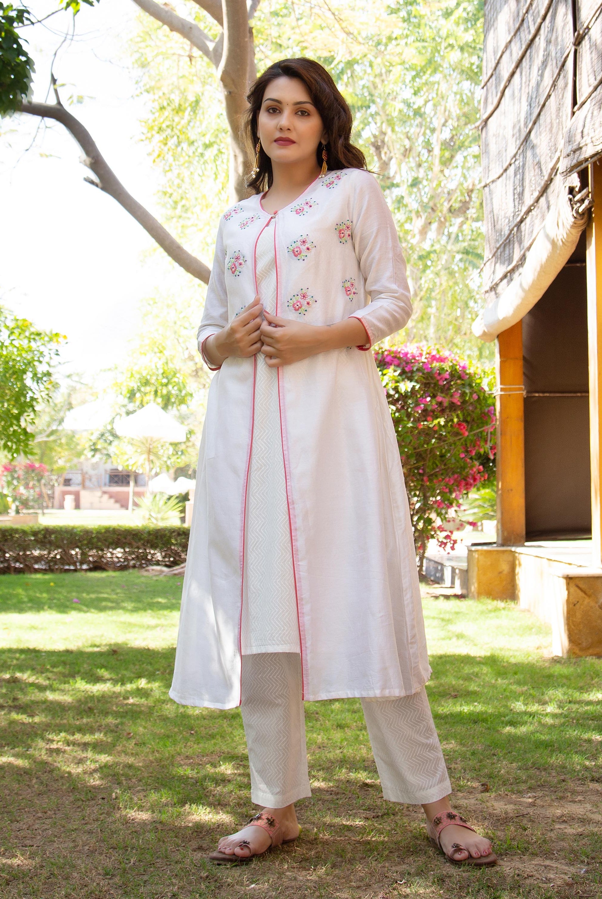 White hand-embroidered floral kurta with pink piping and geometric pattern pants on model.