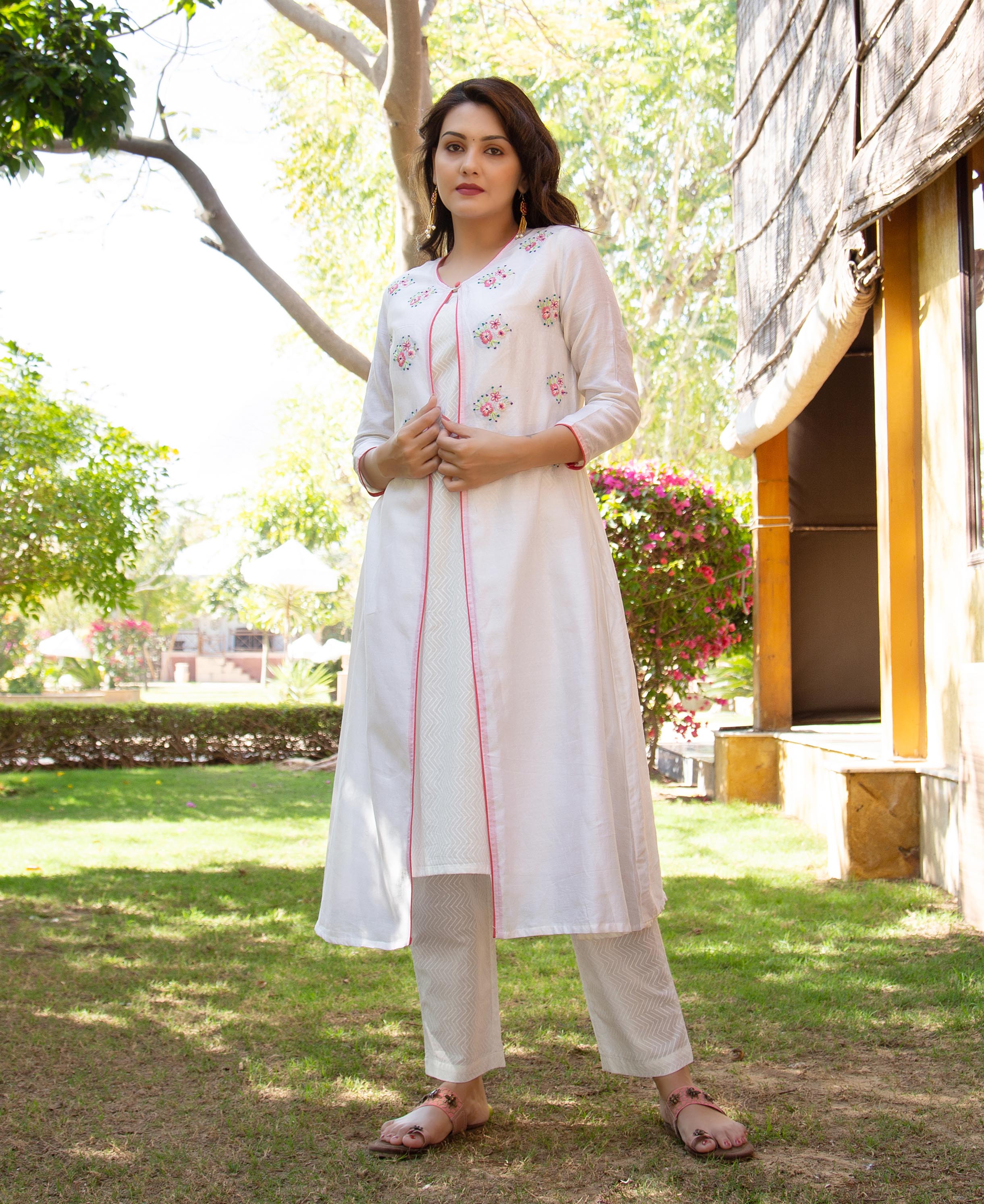 White hand-embroidered floral kurta with pink piping and geometric pattern pants on model.
