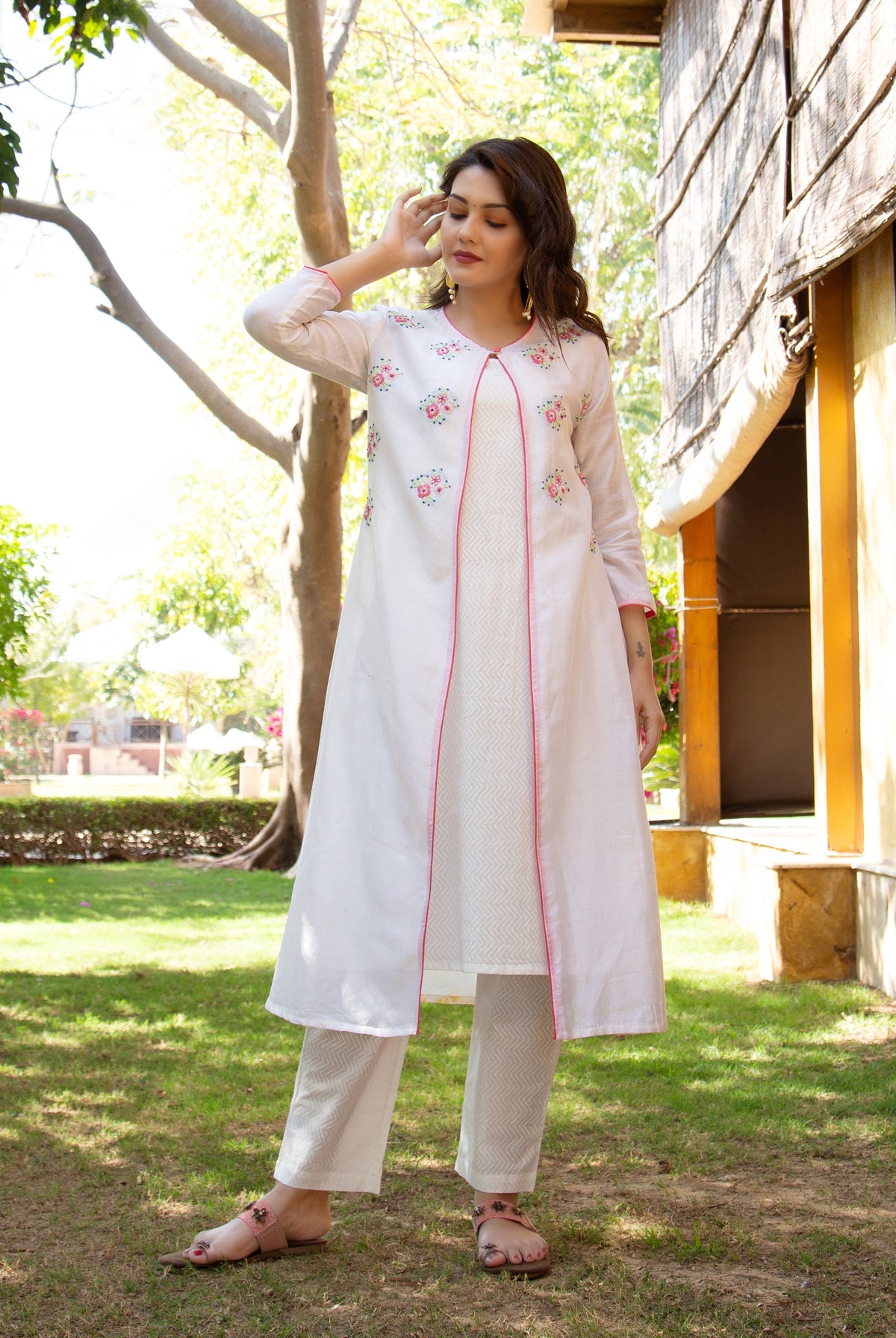 Model in a white hand-embroidered layered kurta with pink trim and block-printed patterned pants.