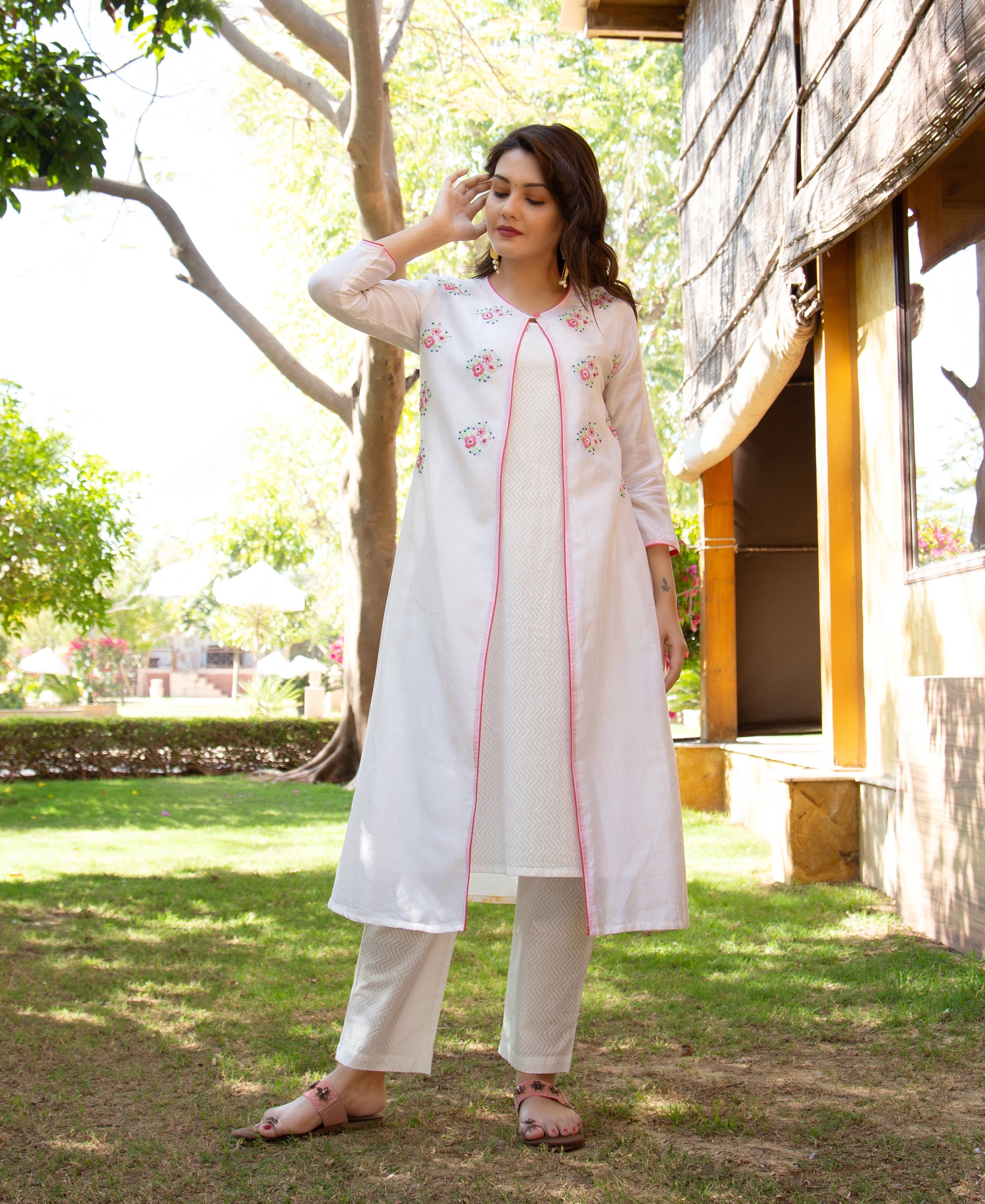 Model in a white hand-embroidered layered kurta with pink trim and block-printed patterned pants.
