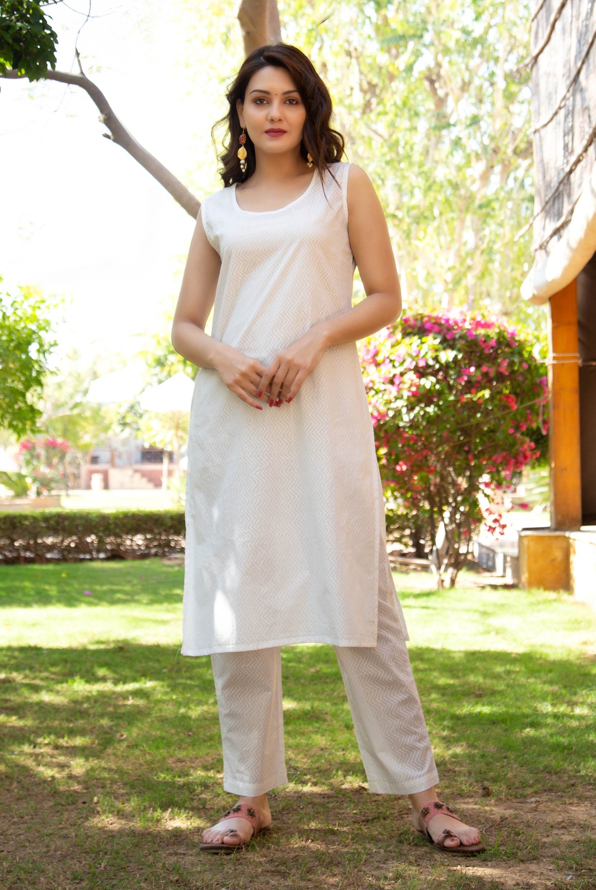 Full-length woman modeling a white hand-block-printed sleeveless kurta and pants with zigzag pattern.