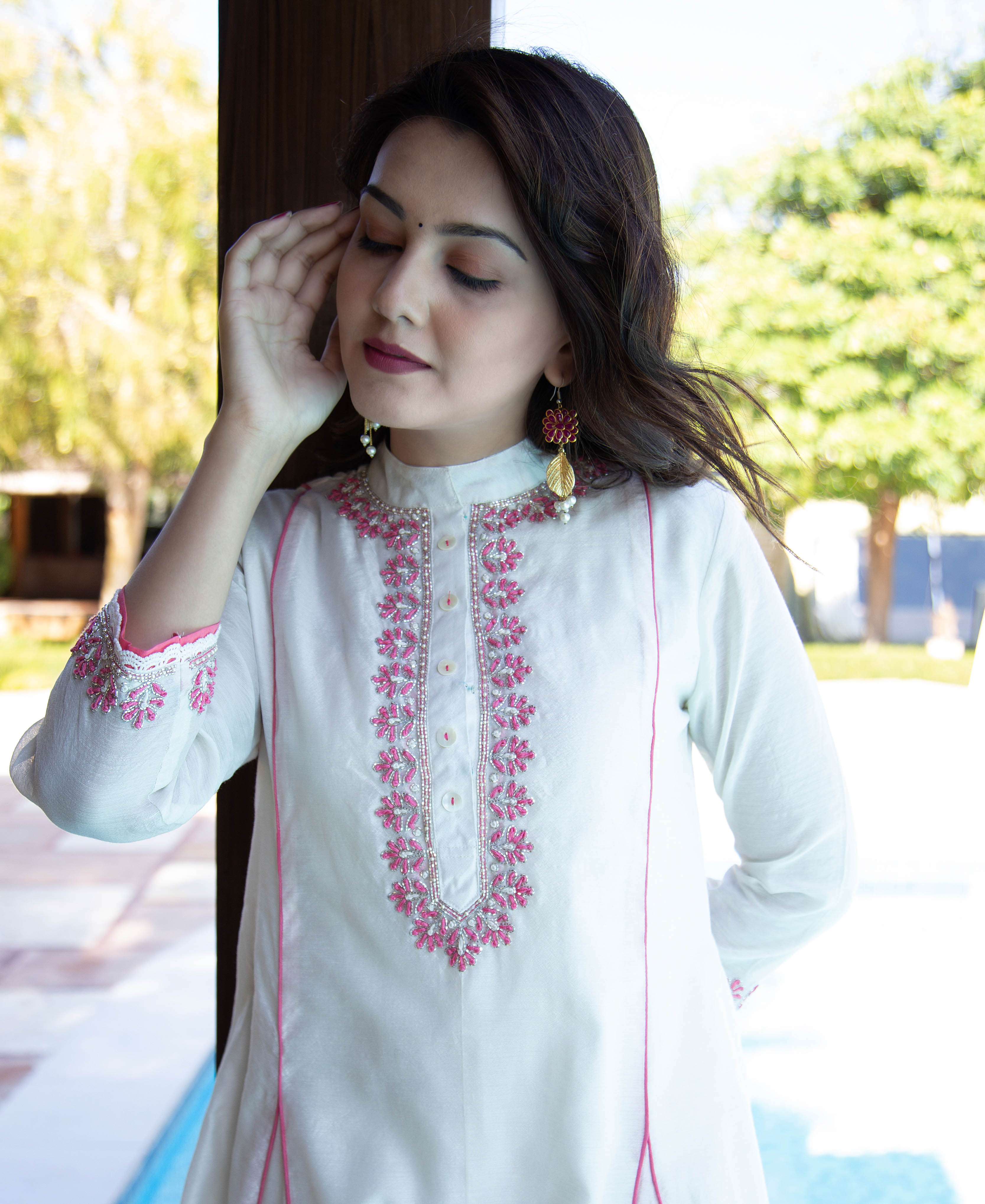 Model wearing off-white kurta with detailed pink hand-embroidered yoke and cuffs.