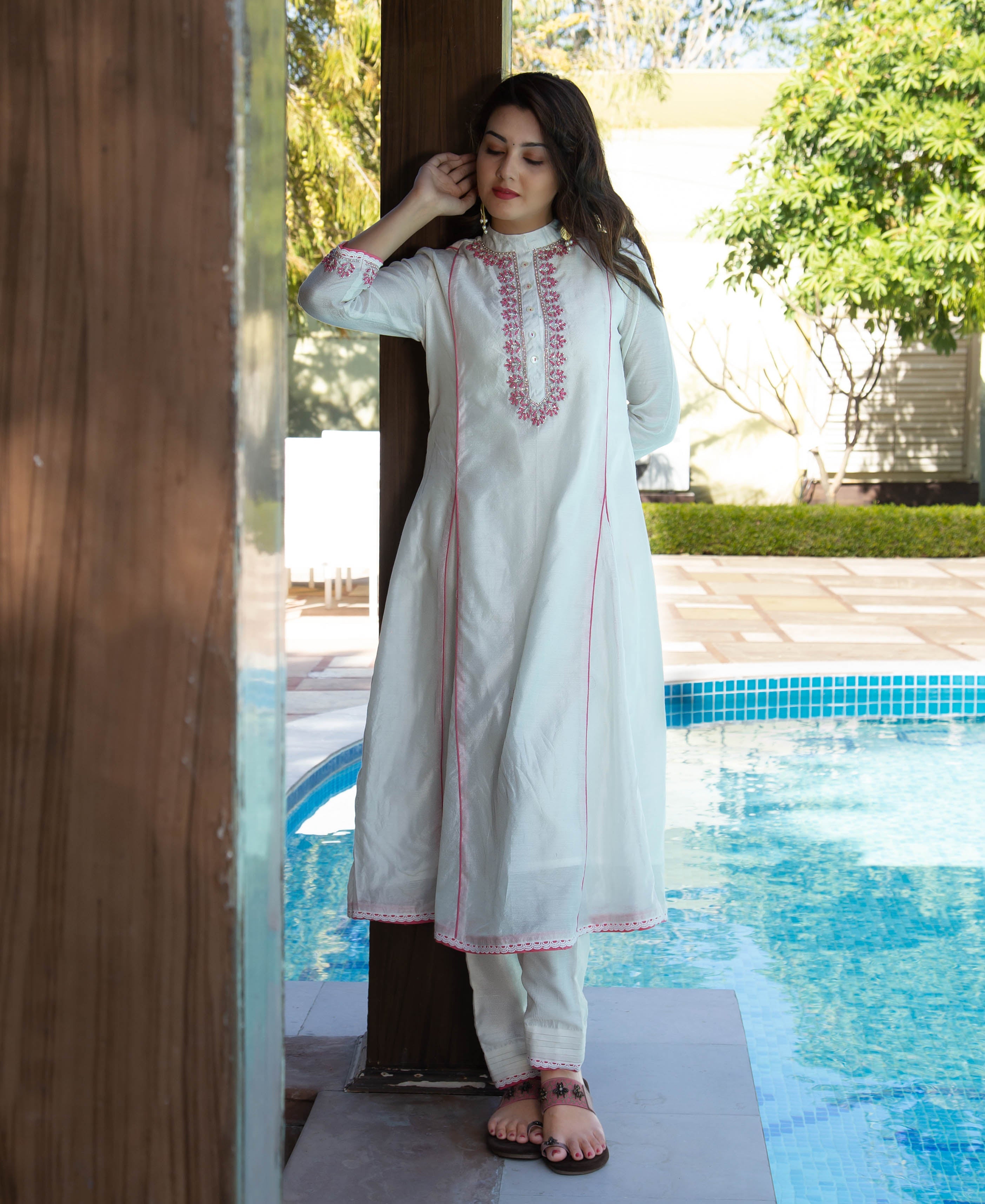 Model in white A-line kurta with pink hand embroidery and piping, front full view.