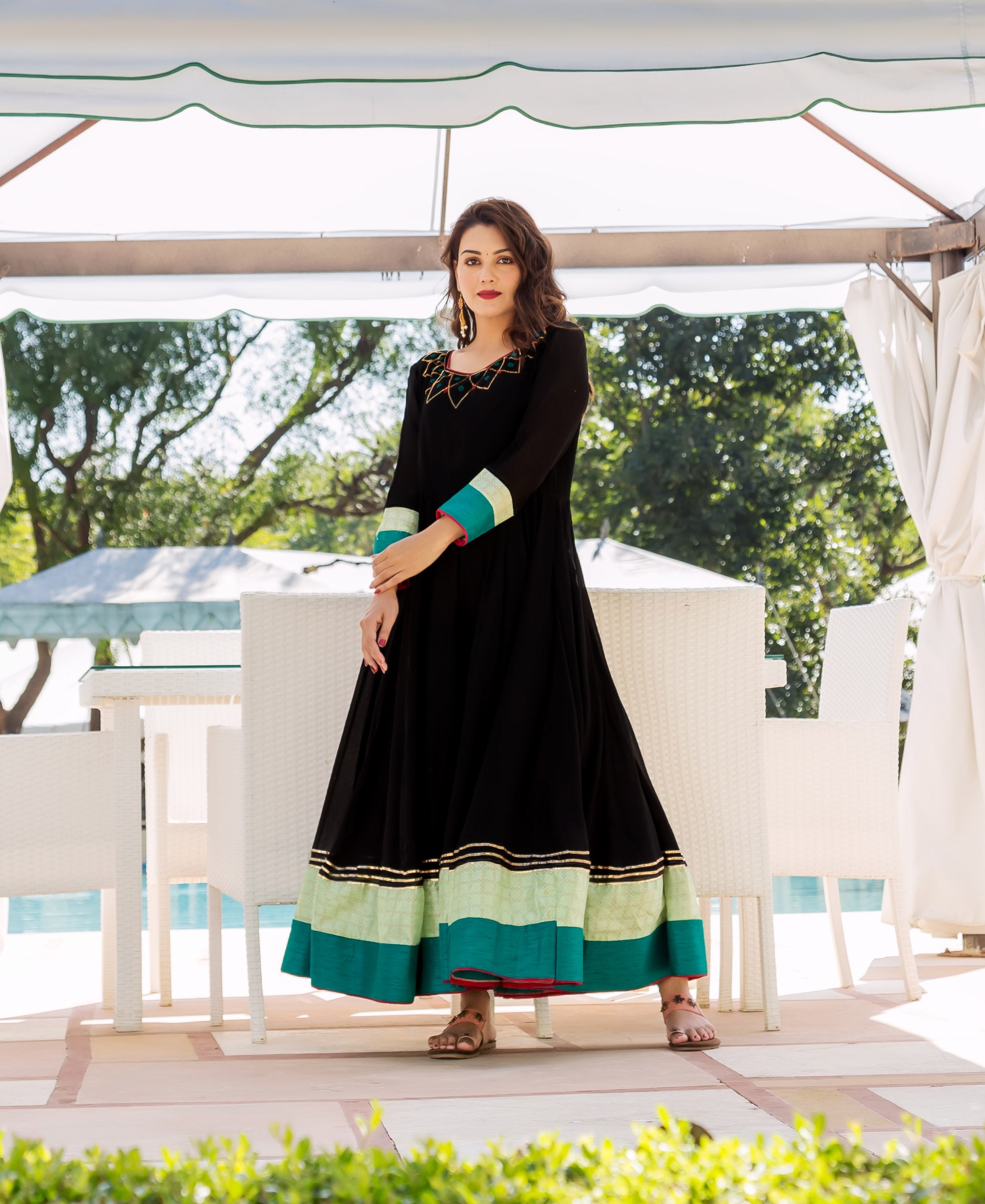 Model in full-front black Anarkali dress with colorful yoke pattern and lime-teal banded hem.