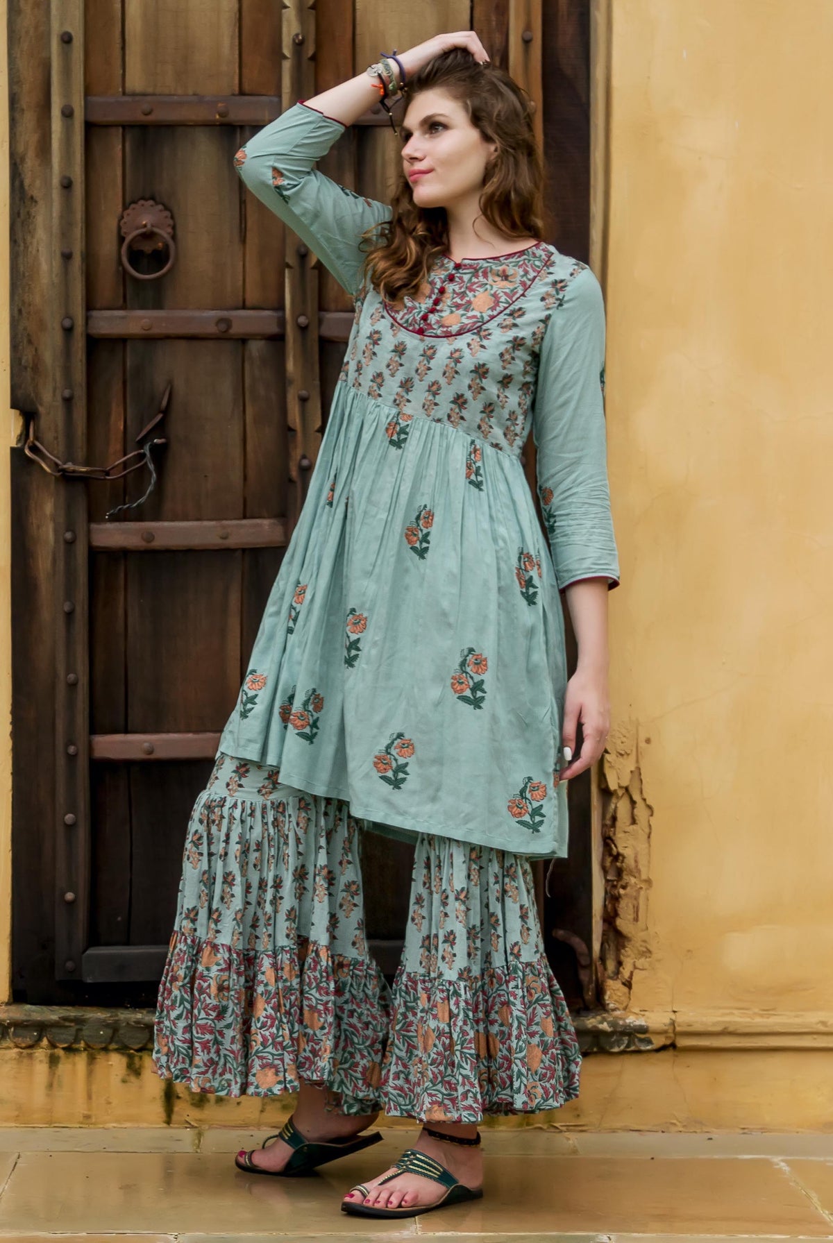 Full body of a model in a light blue hand block printed floral kurta and sharara.