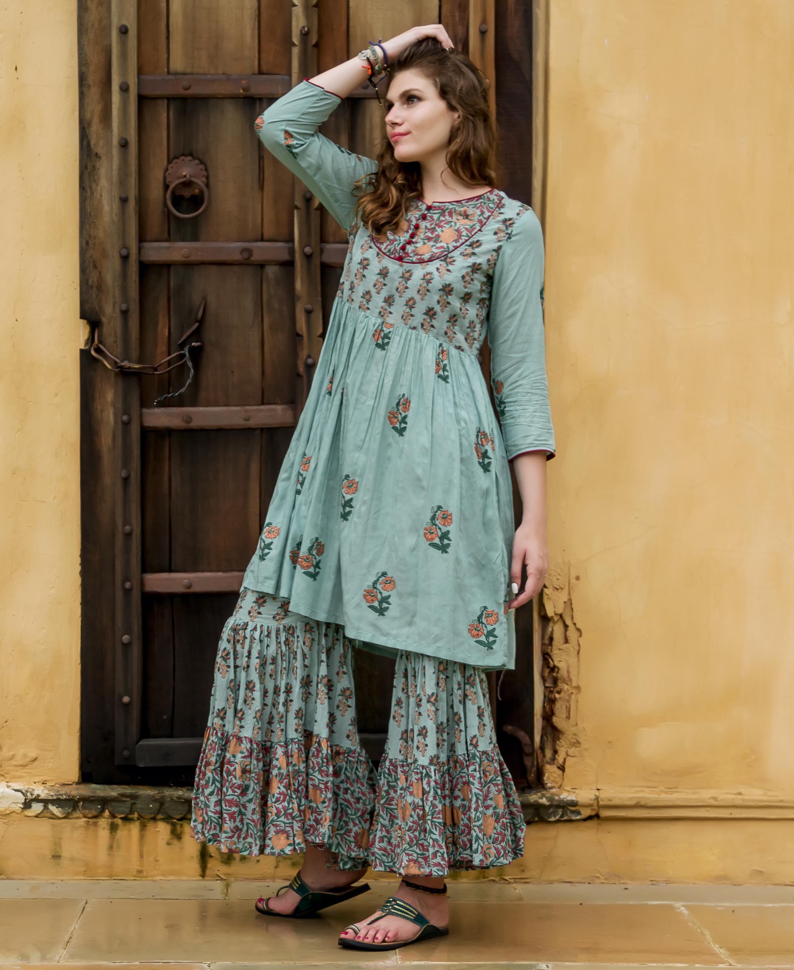 Full body of a model in a light blue hand block printed floral kurta and sharara.