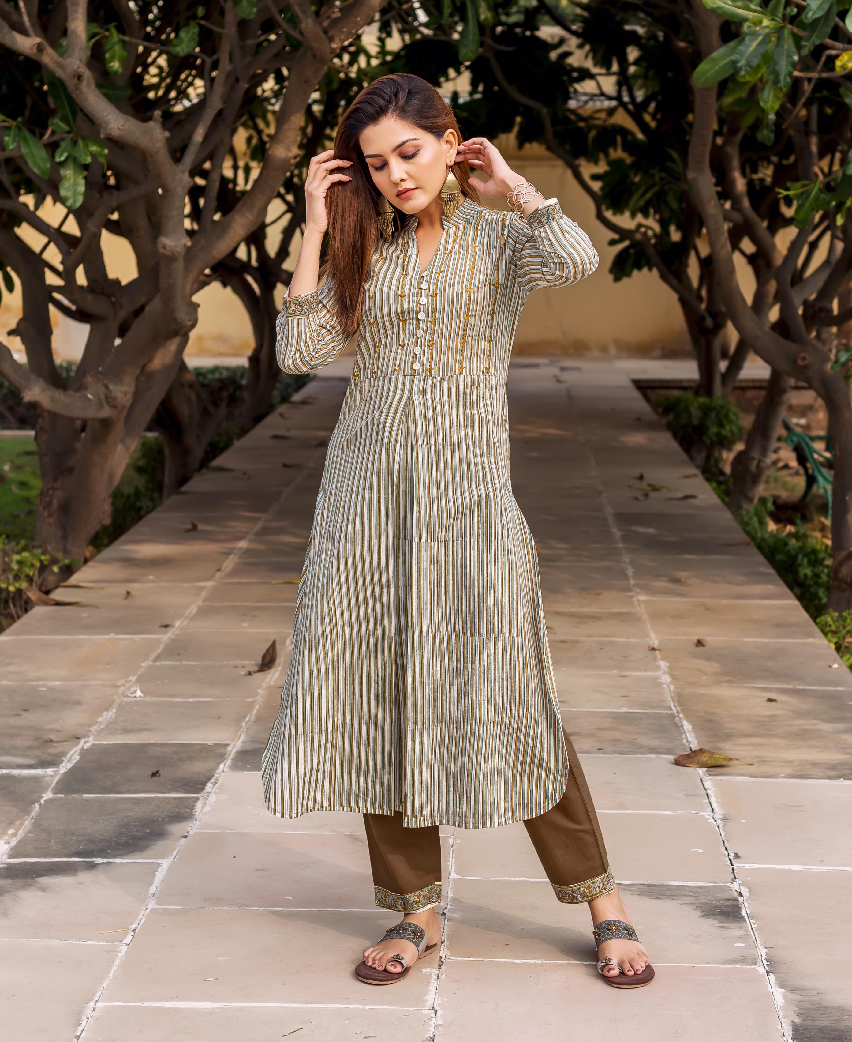 Full-length model wears olive green striped embroidered kurta with brown pants and sandals.