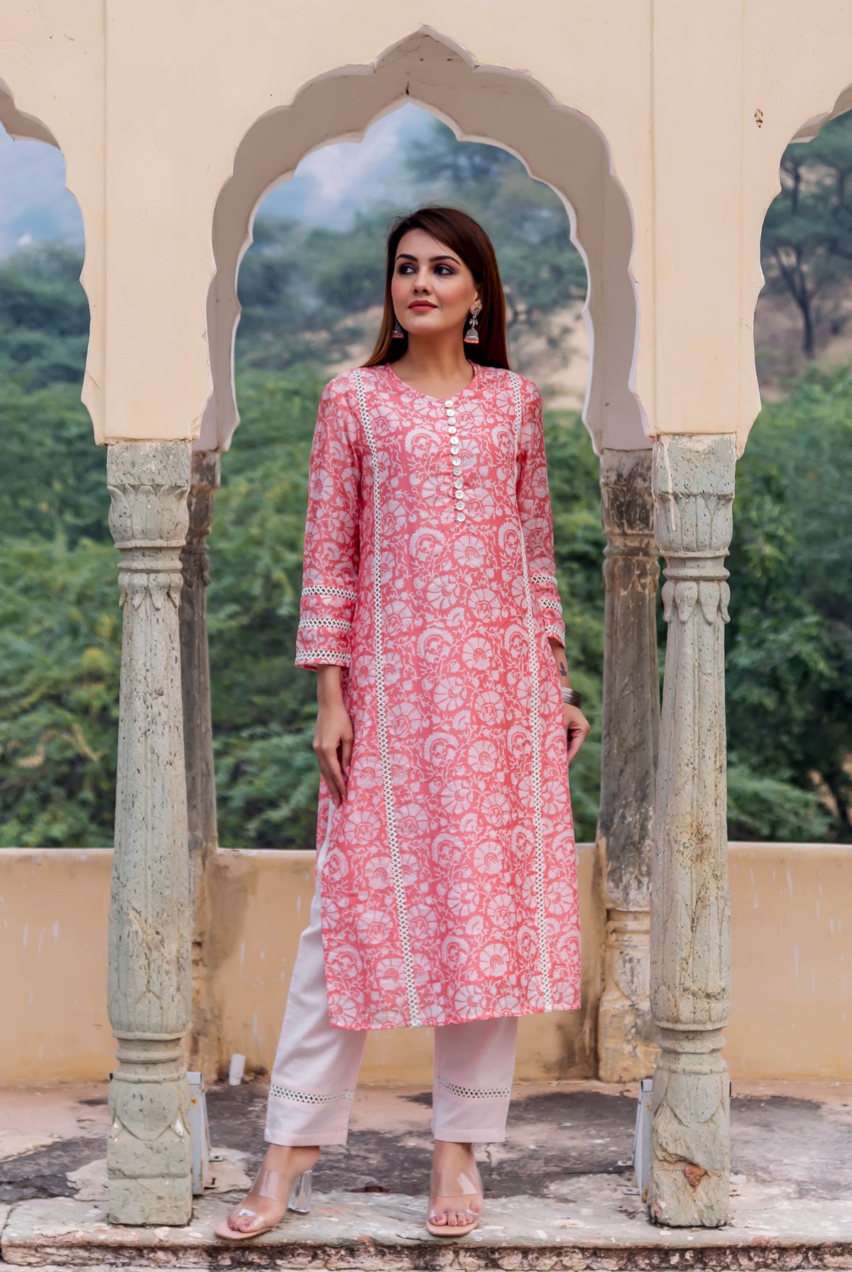 Model wearing a peach hand-block printed floral kurta with white lace and light pink pants.