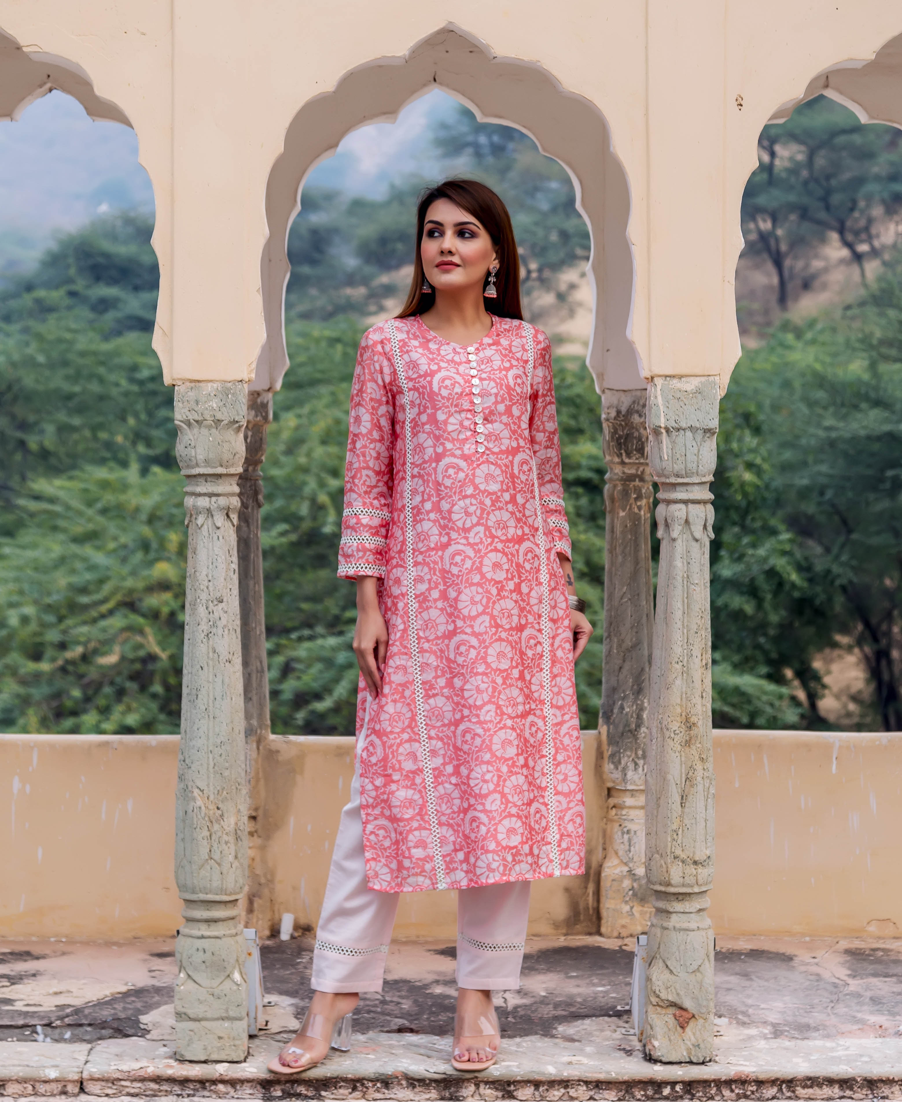 Model wearing a peach hand-block printed floral kurta with white lace and light pink pants.