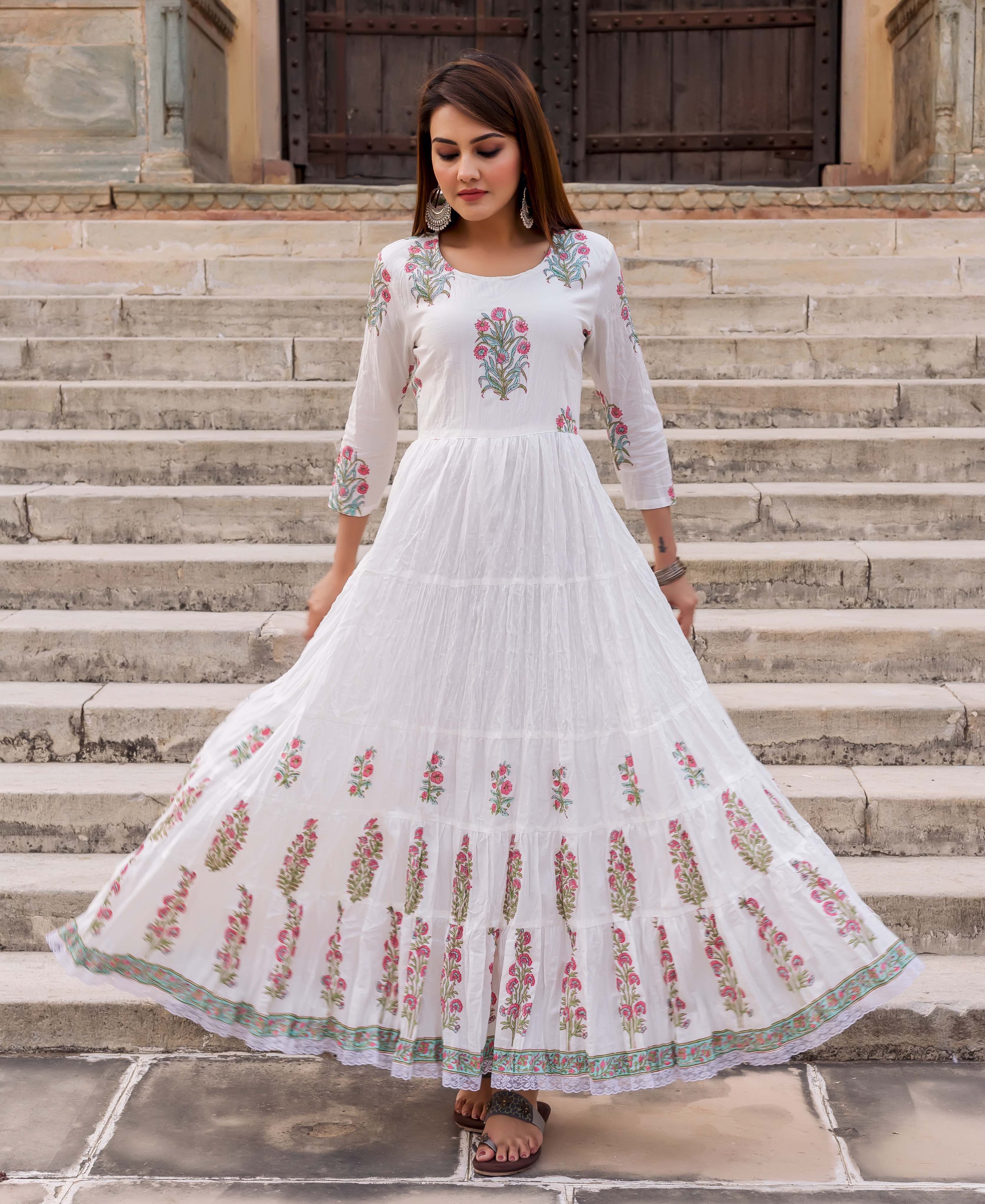 Front view of model in white tiered dress with pink and green floral butta print.