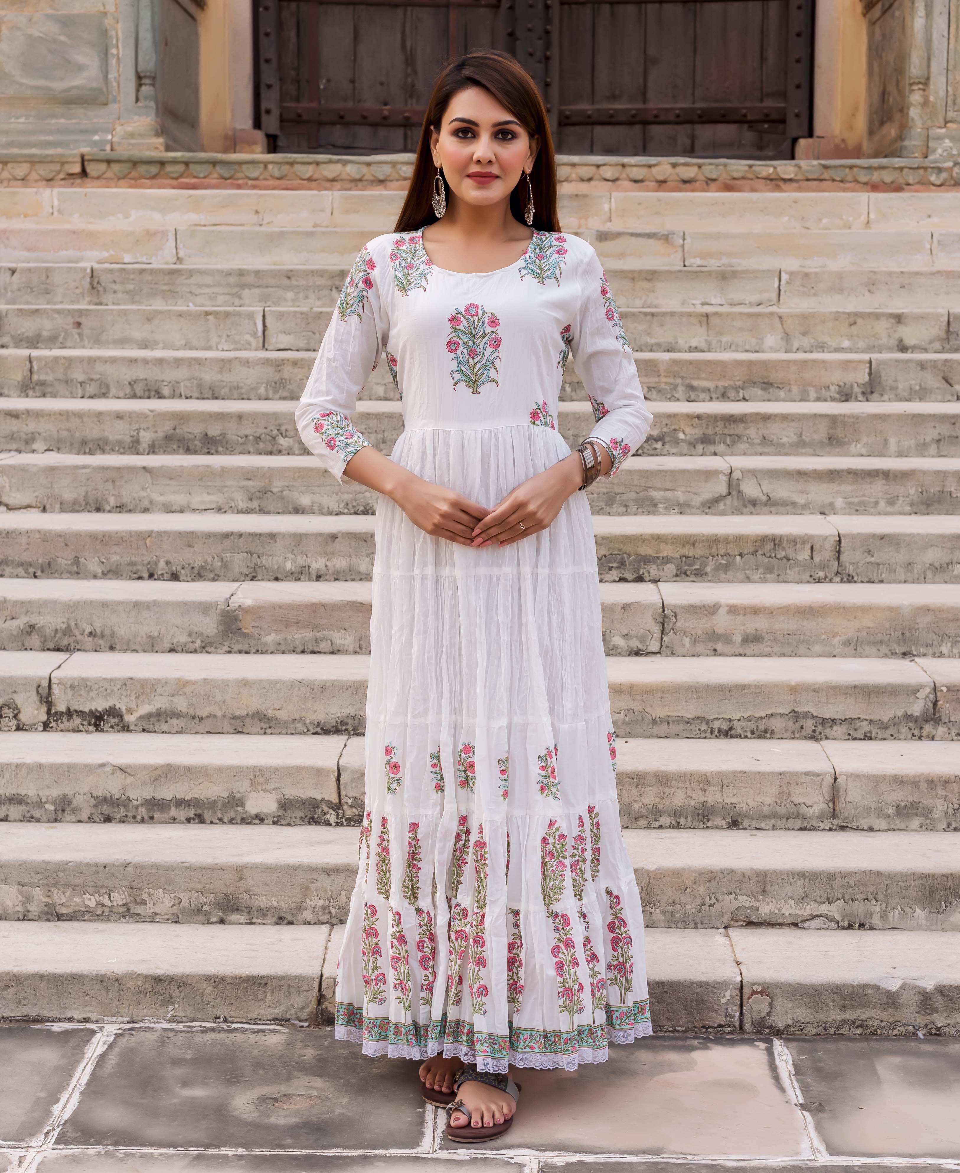 Model wearing a white tiered dress with pink and green floral butta print.