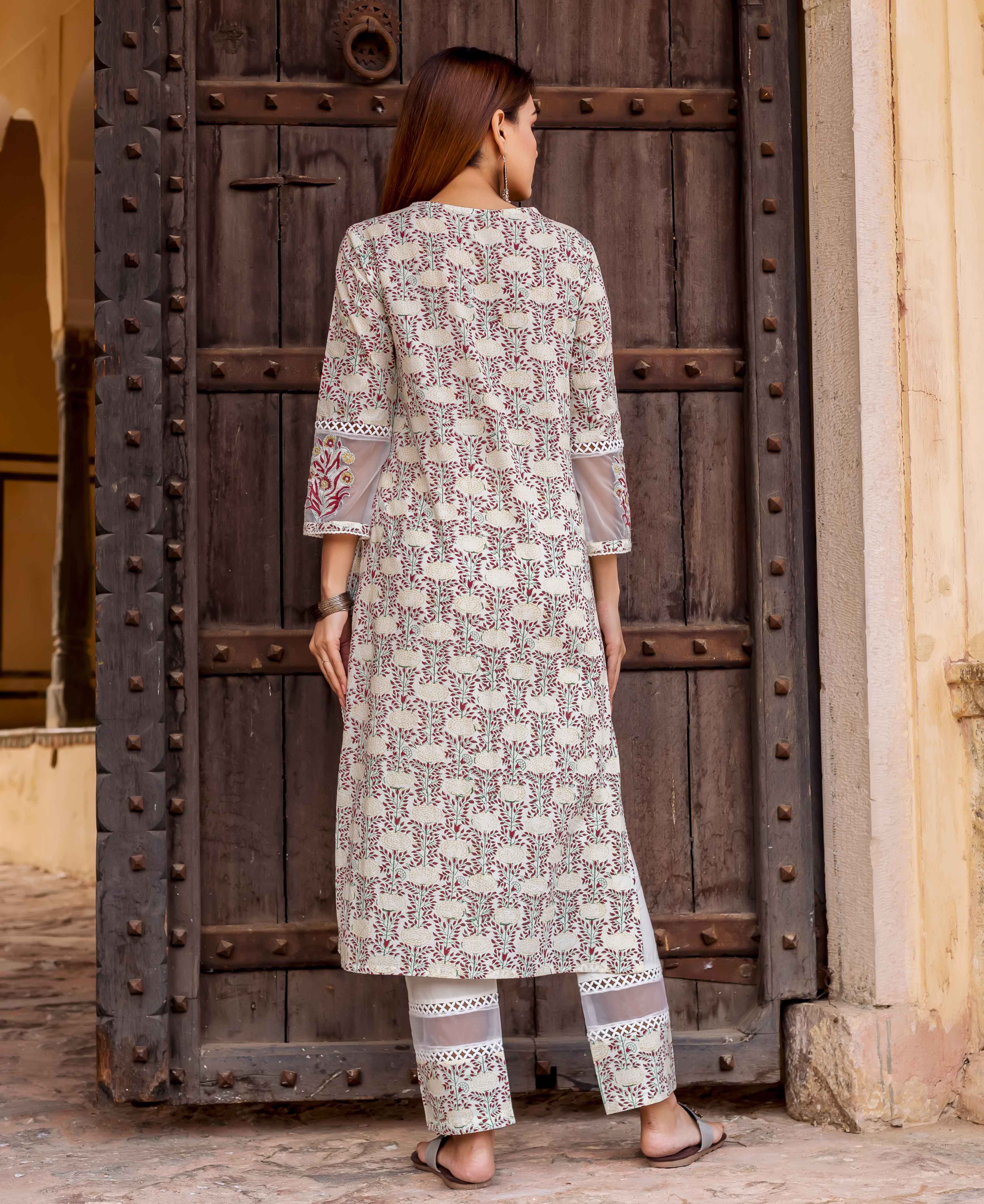 Back view of woman in cream, maroon, teal block-printed kurta and pants, sheer embroidered cuffs.