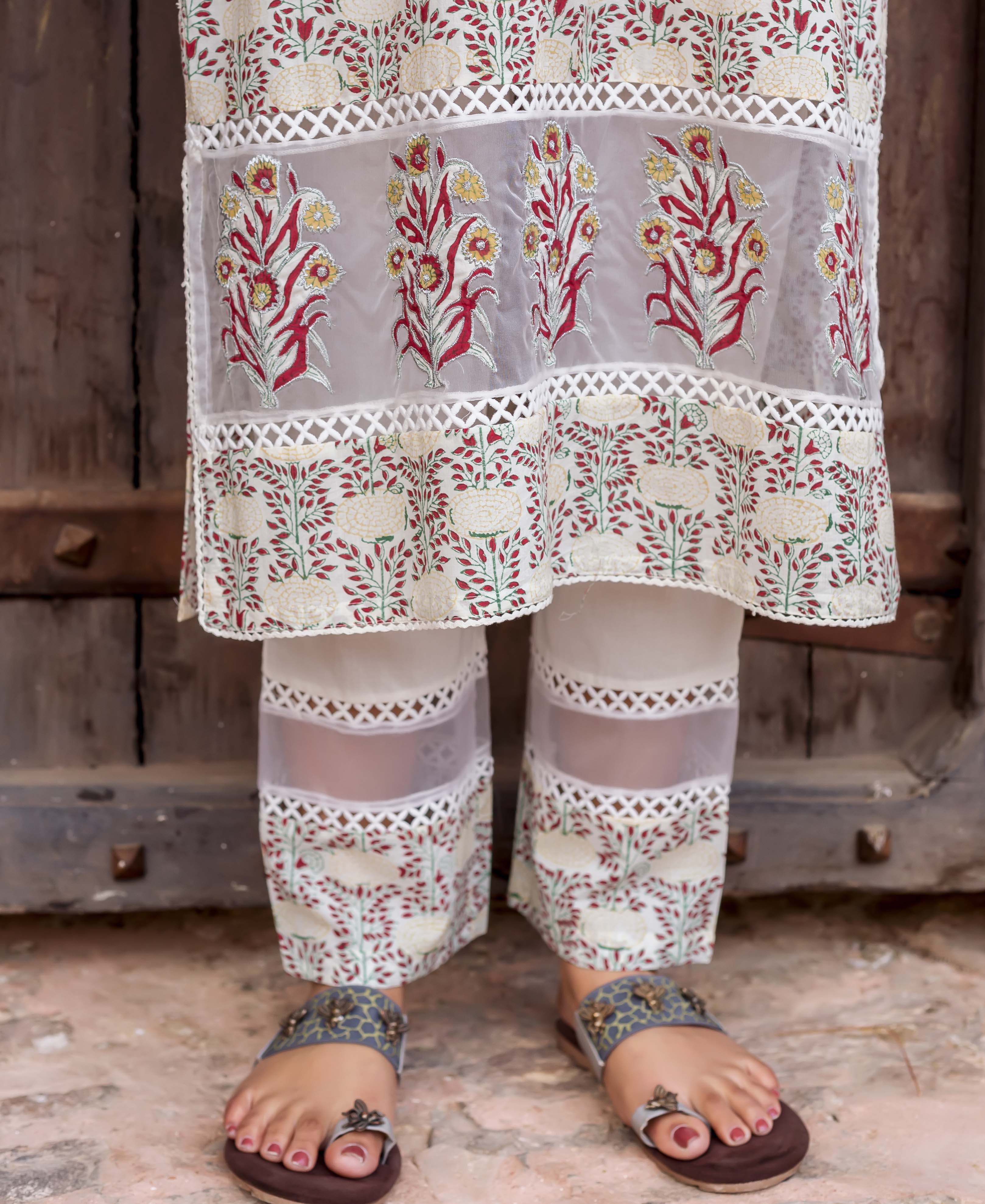 Close-up of a cream block-printed kurta with red, yellow floral embroidery and sheer lace panels.