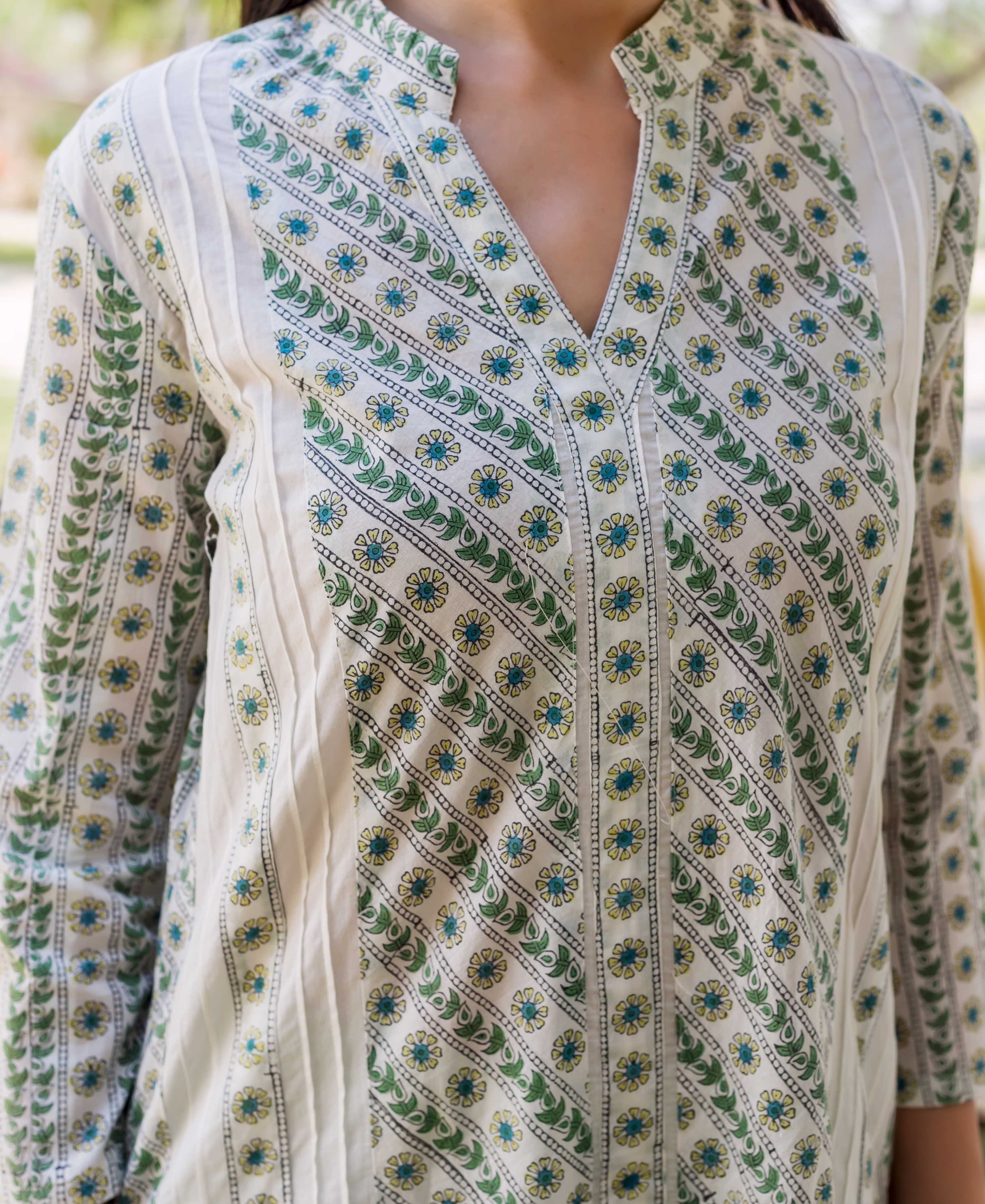 A model wearing a white, hand-block-printed kurta with green and blue floral patterns.
