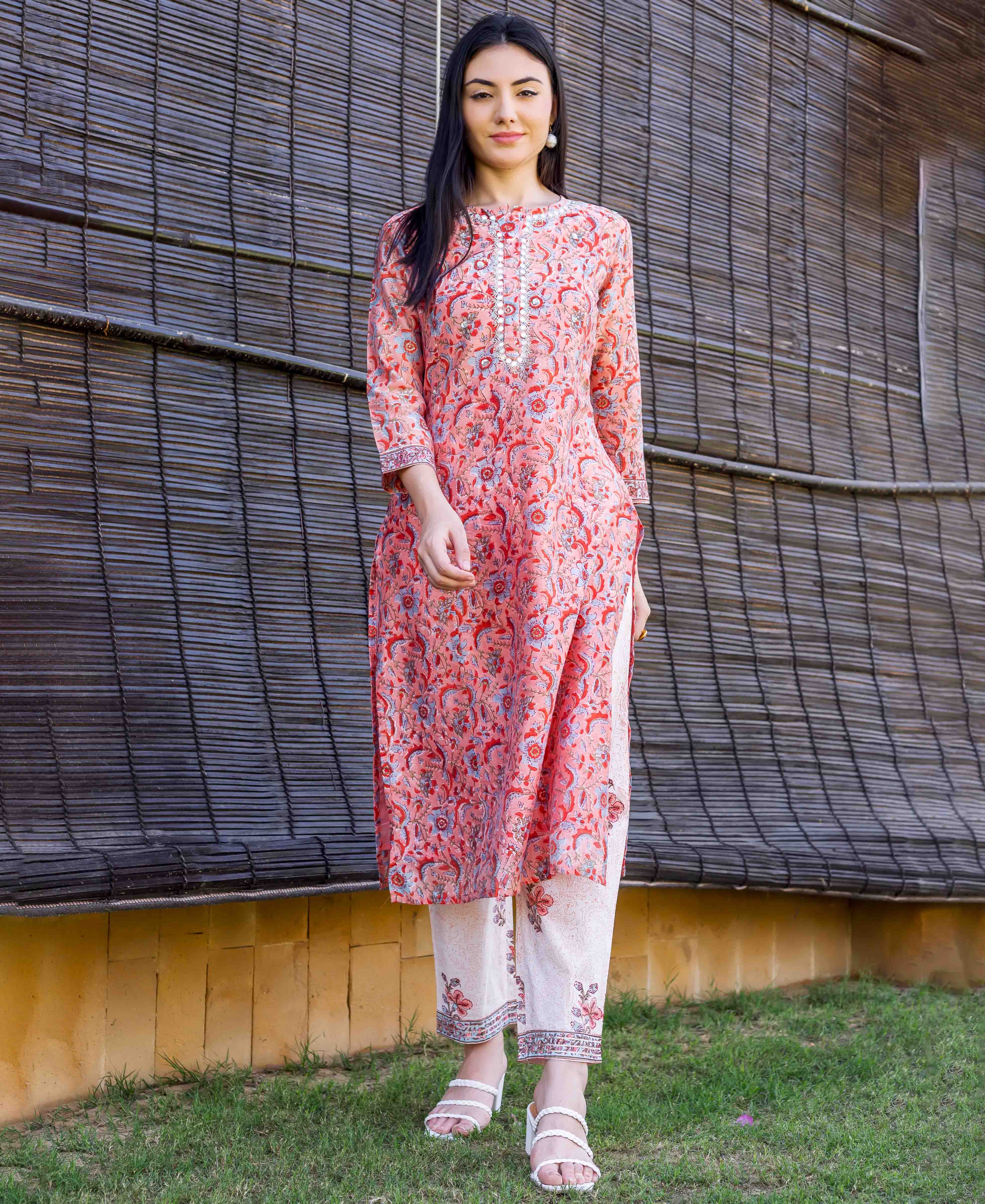 Model wears a peach floral block-printed straight kurta with an embroidered neckline.