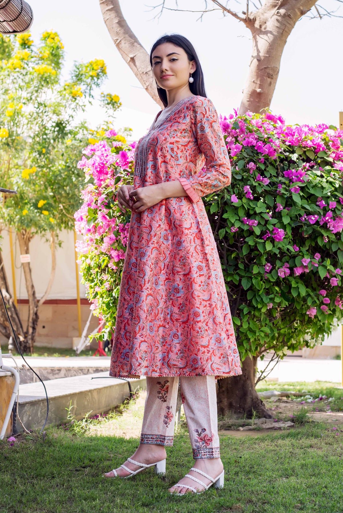 Model in a coral pink A-line kurta with blue floral block print and matching pants.