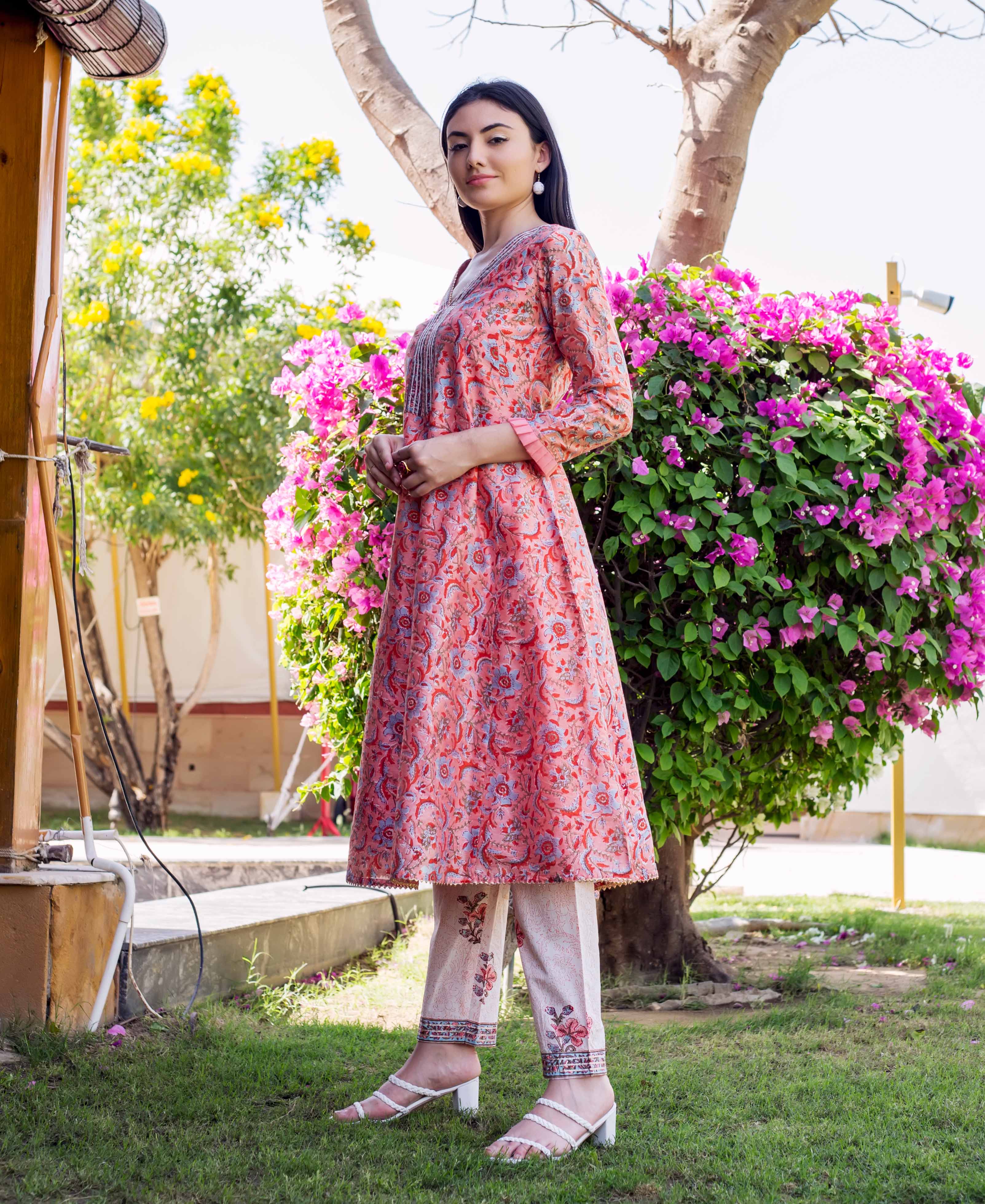 Model in a coral pink A-line kurta with blue floral block print and matching pants.