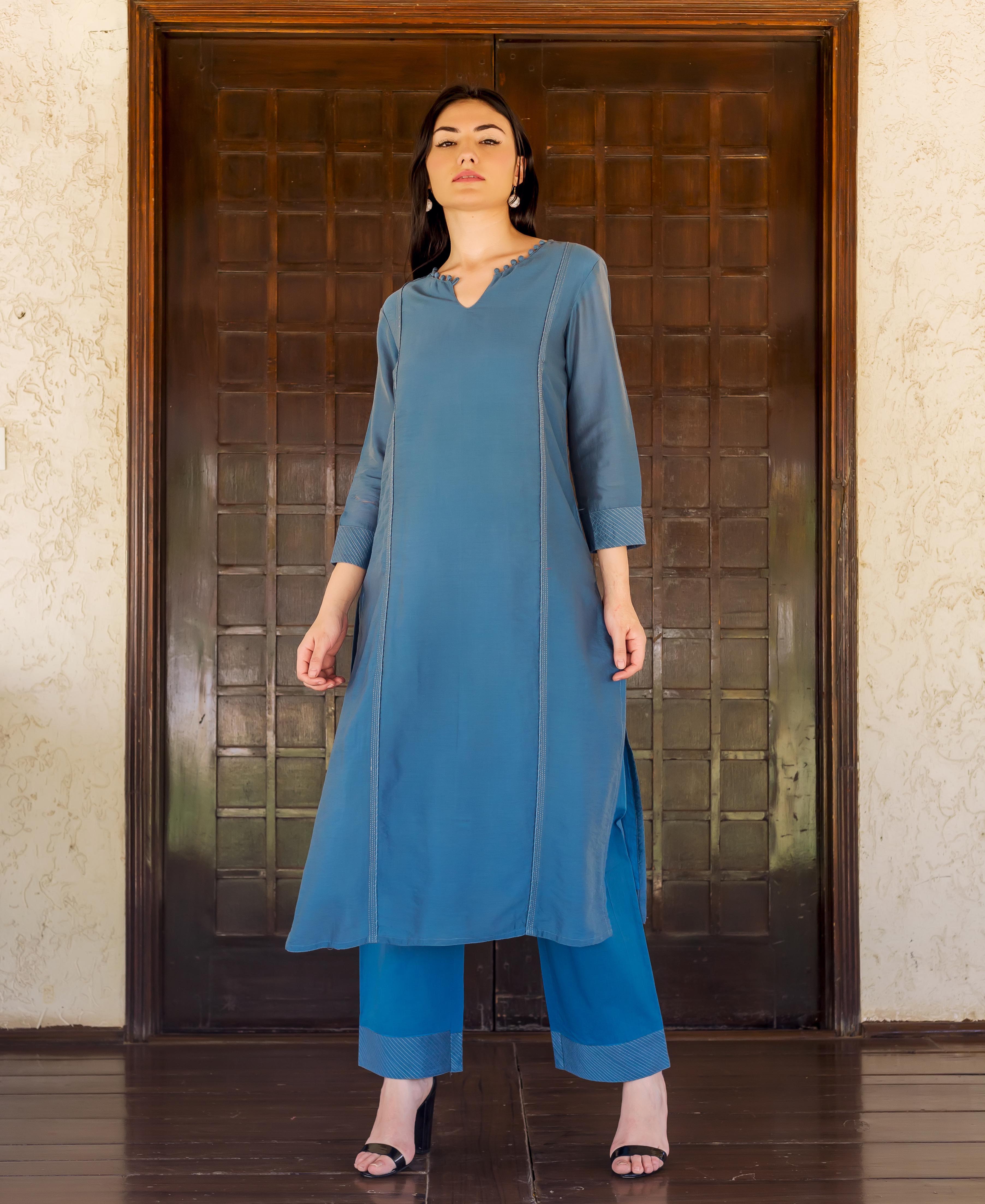 Front view model in Prussian blue embroidered kurta with white vertical stitching and blue striped pants.