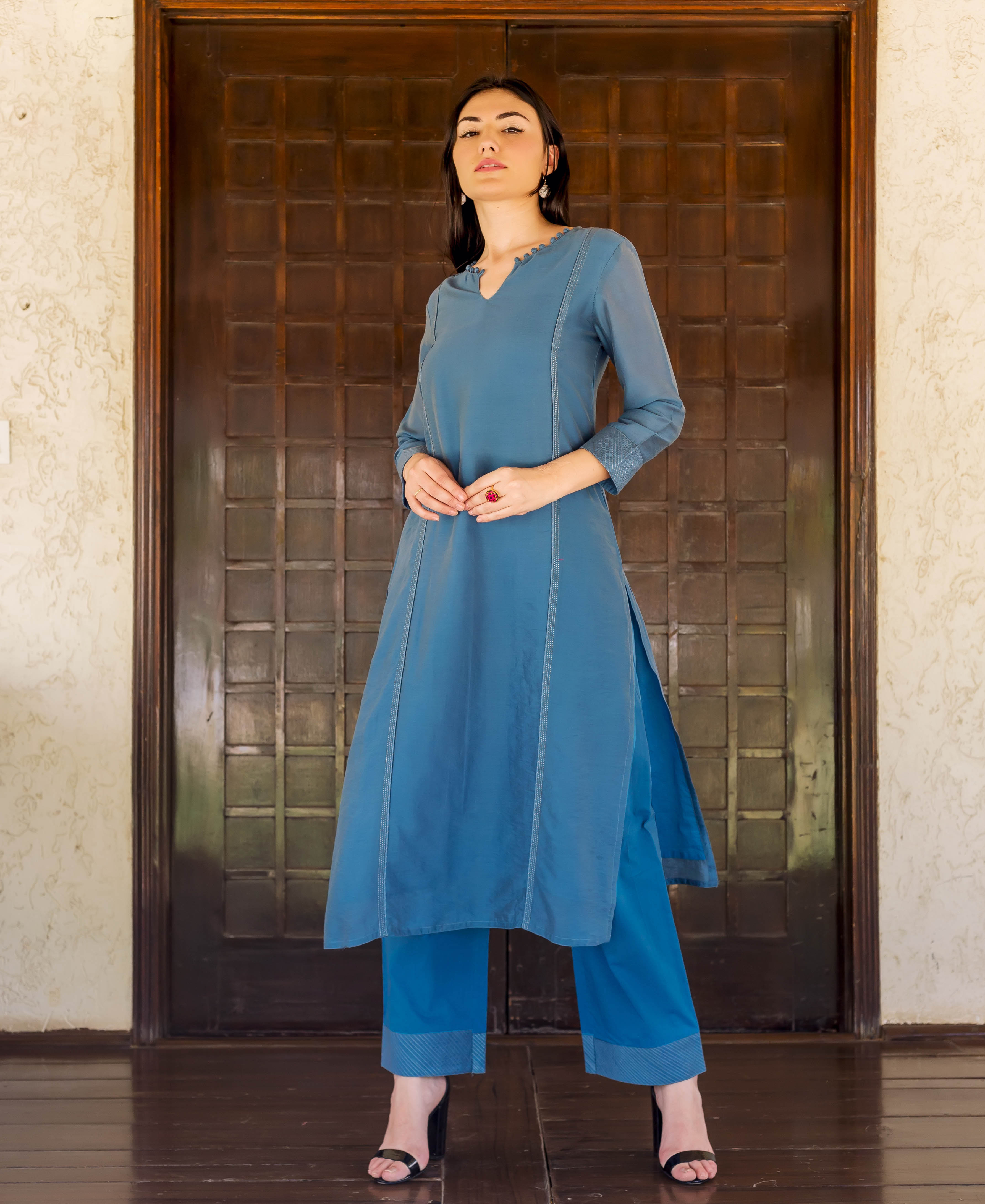 Full shot of model wearing a Prussian blue embroidered kurta with matching straight pants.