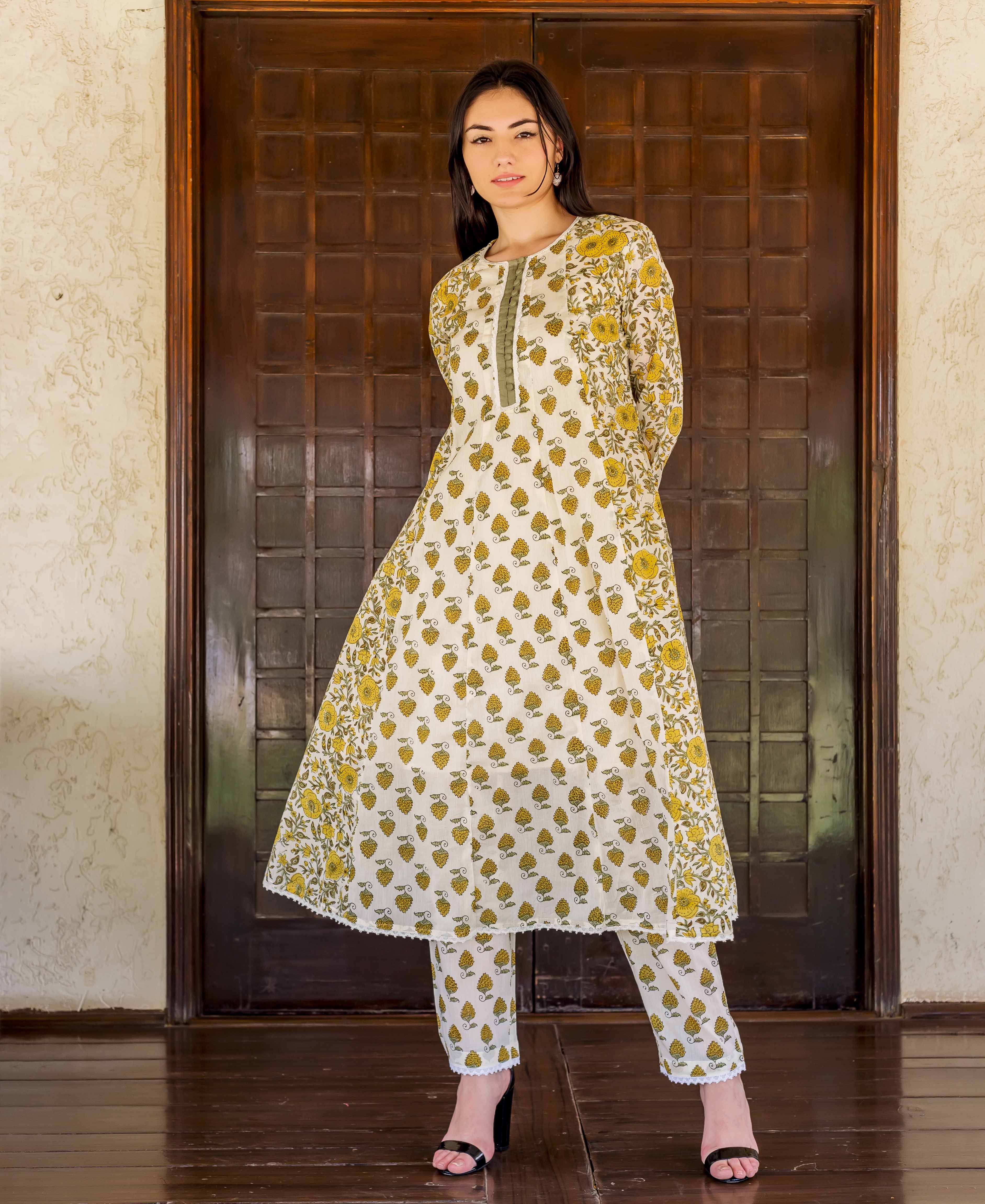 Full-length model in white and ochre hand block printed A-line kurta and matching pants.