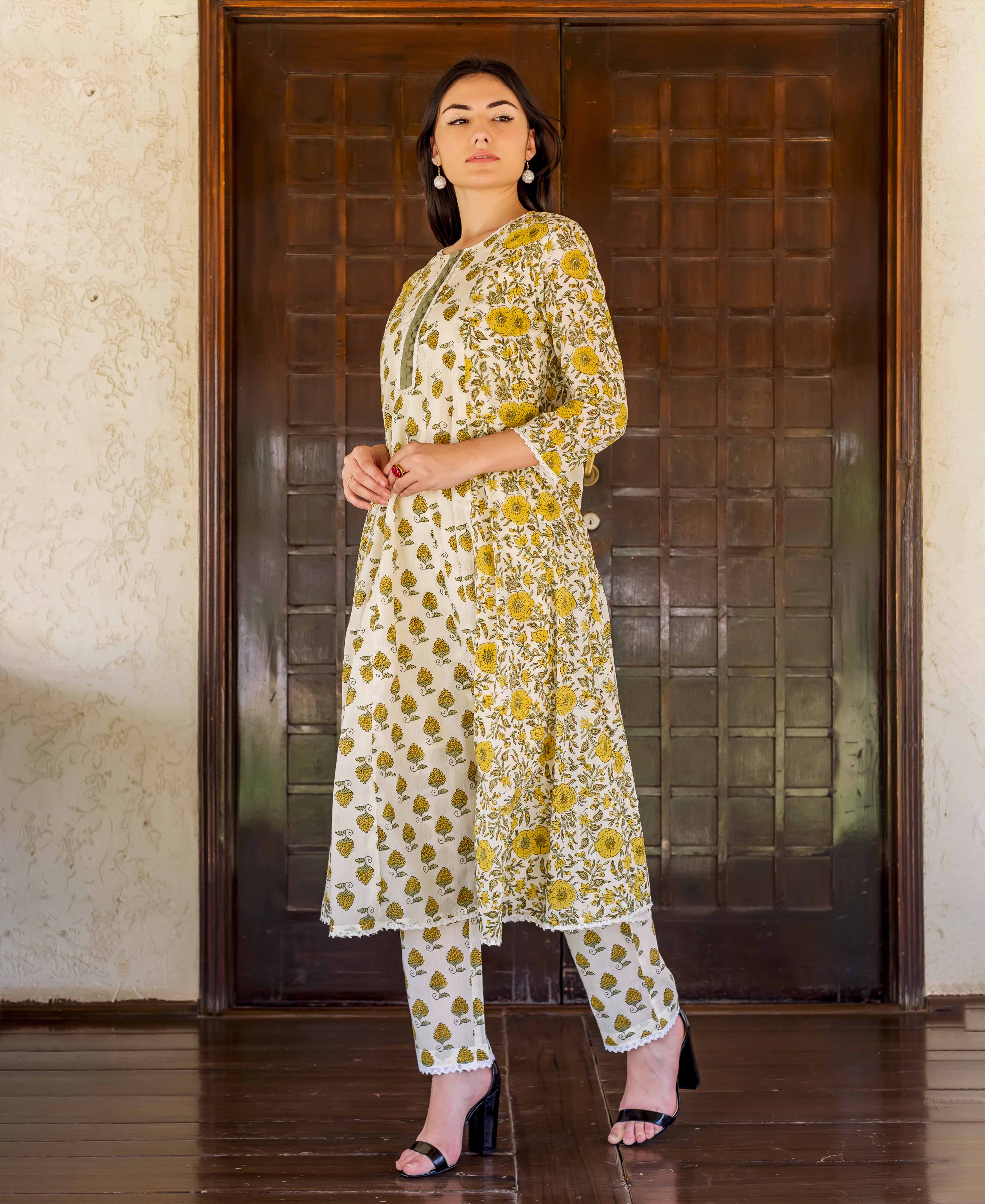 Model wearing a white and ochre hand-block printed A-line kurta with matching cropped trousers.