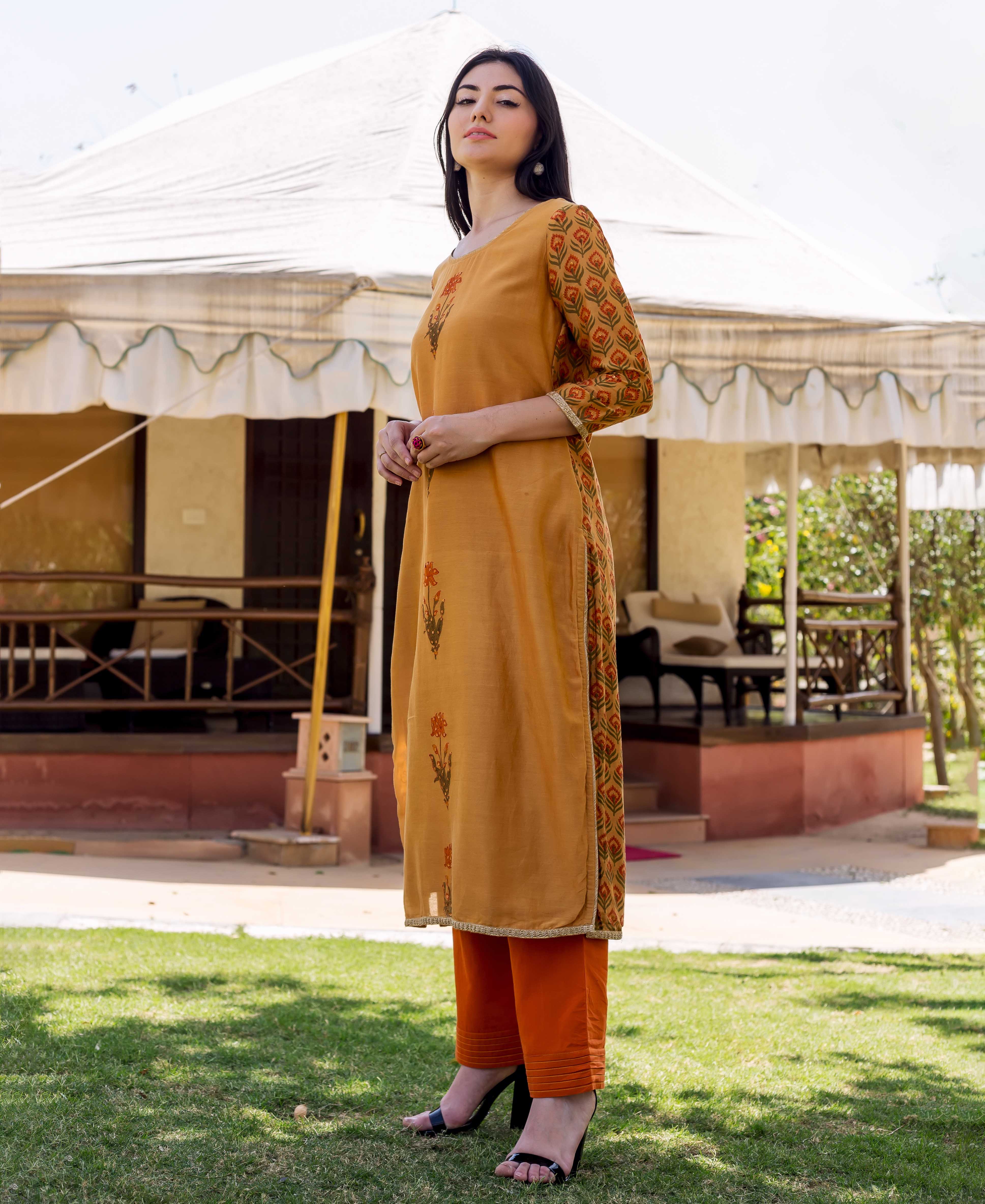 Model wears mustard yellow block-printed floral kurta, geometric sleeves, and orange pants.