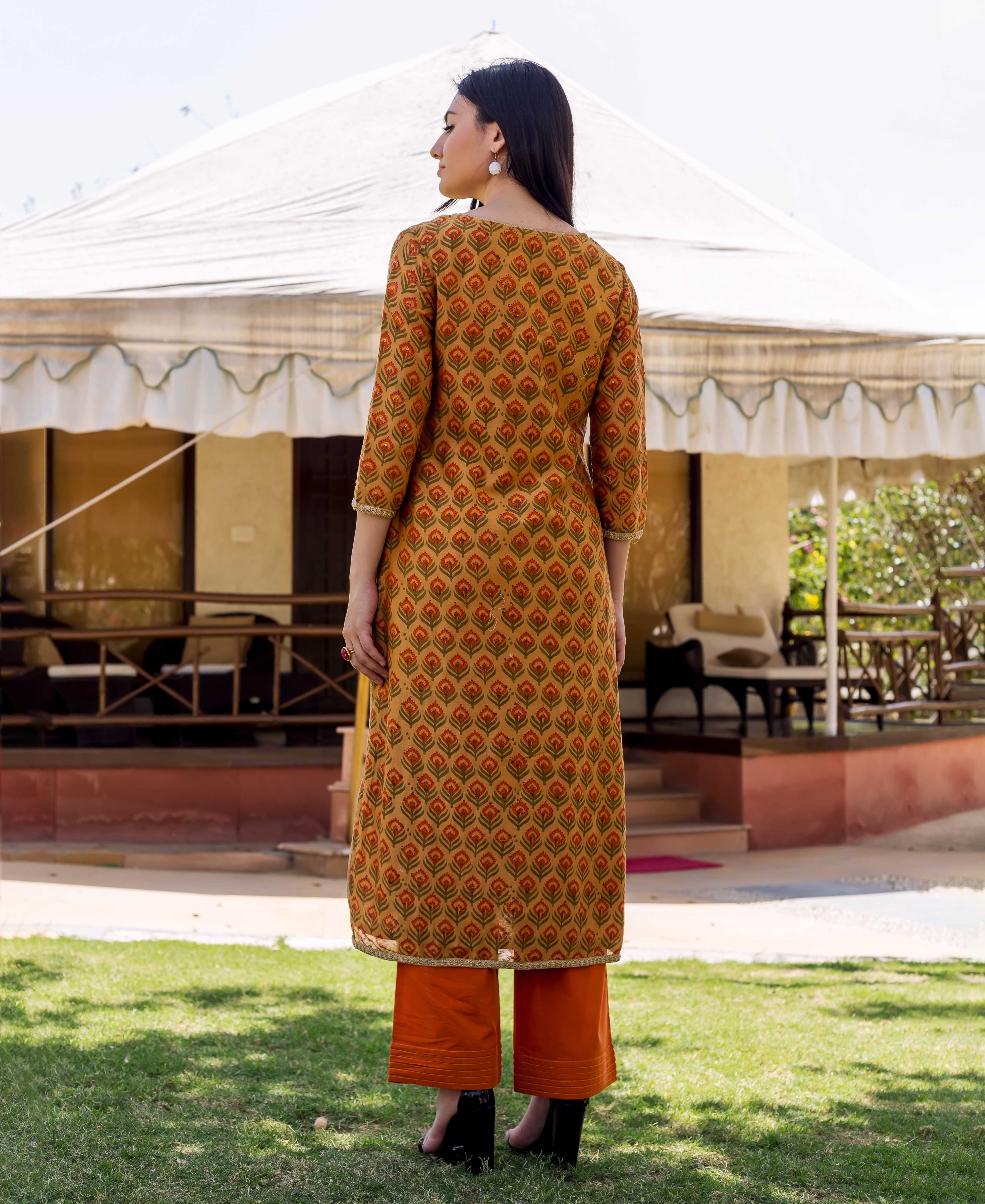 Rear view of woman in mustard block-printed kurta with orange floral motifs and bright orange culottes.