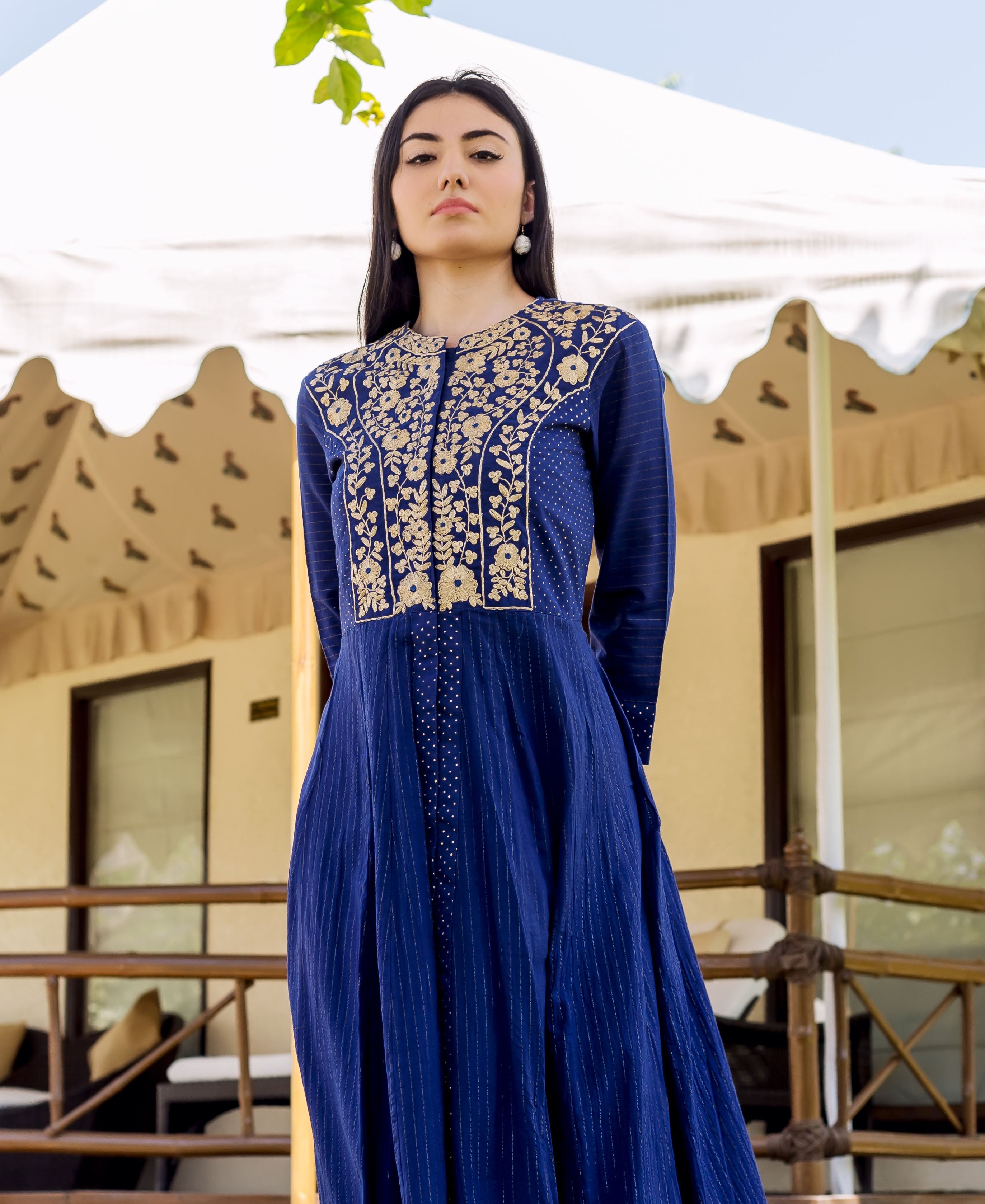 A woman in a royal blue dress with gold embroidery and white dots.