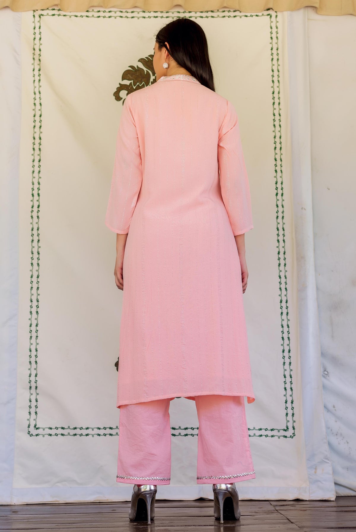 Back view of model in pink straight kurta with subtle stripes and embroidered pants.