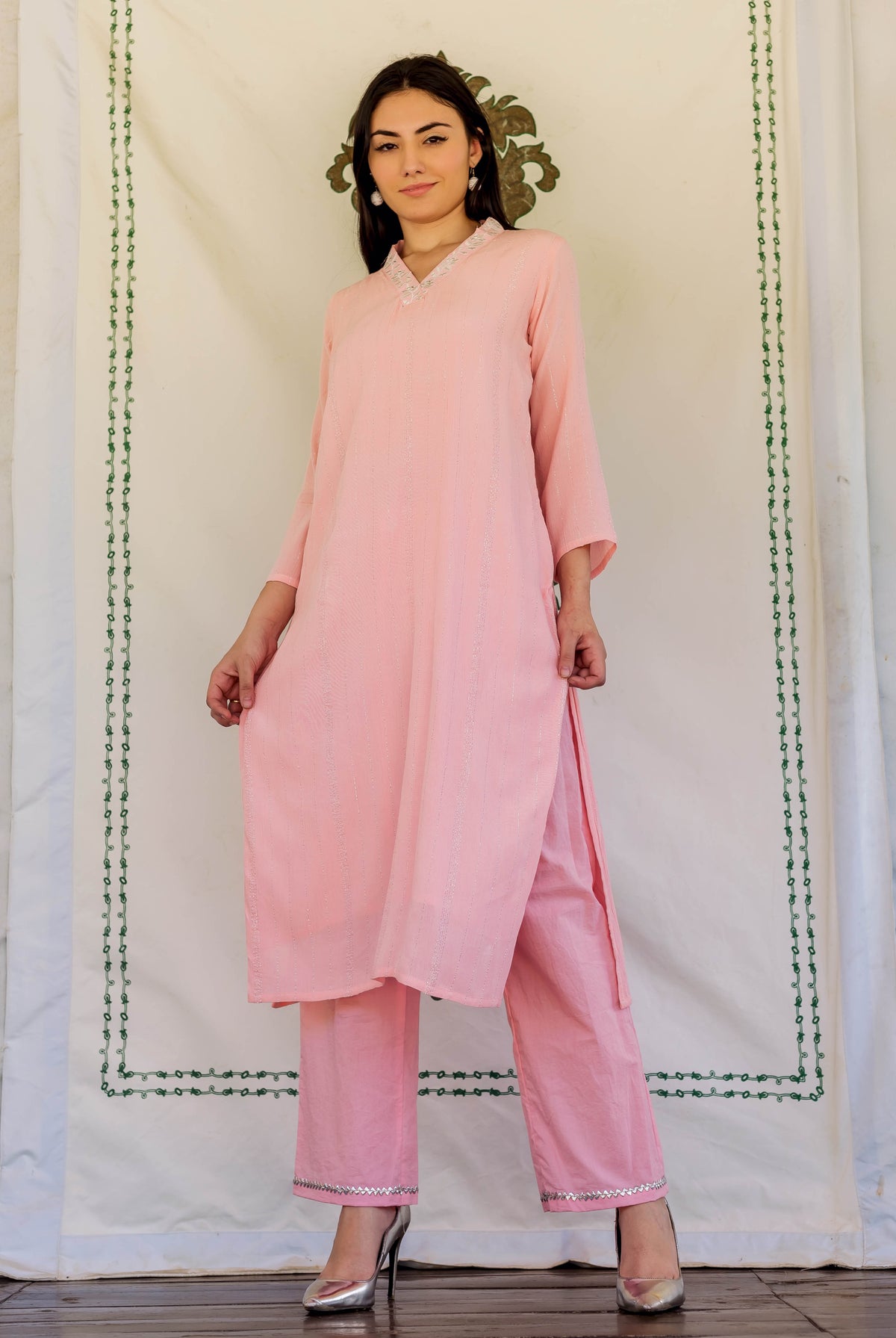 Model in a pink subtly striped kurta set with embroidered neckline and silver trim.