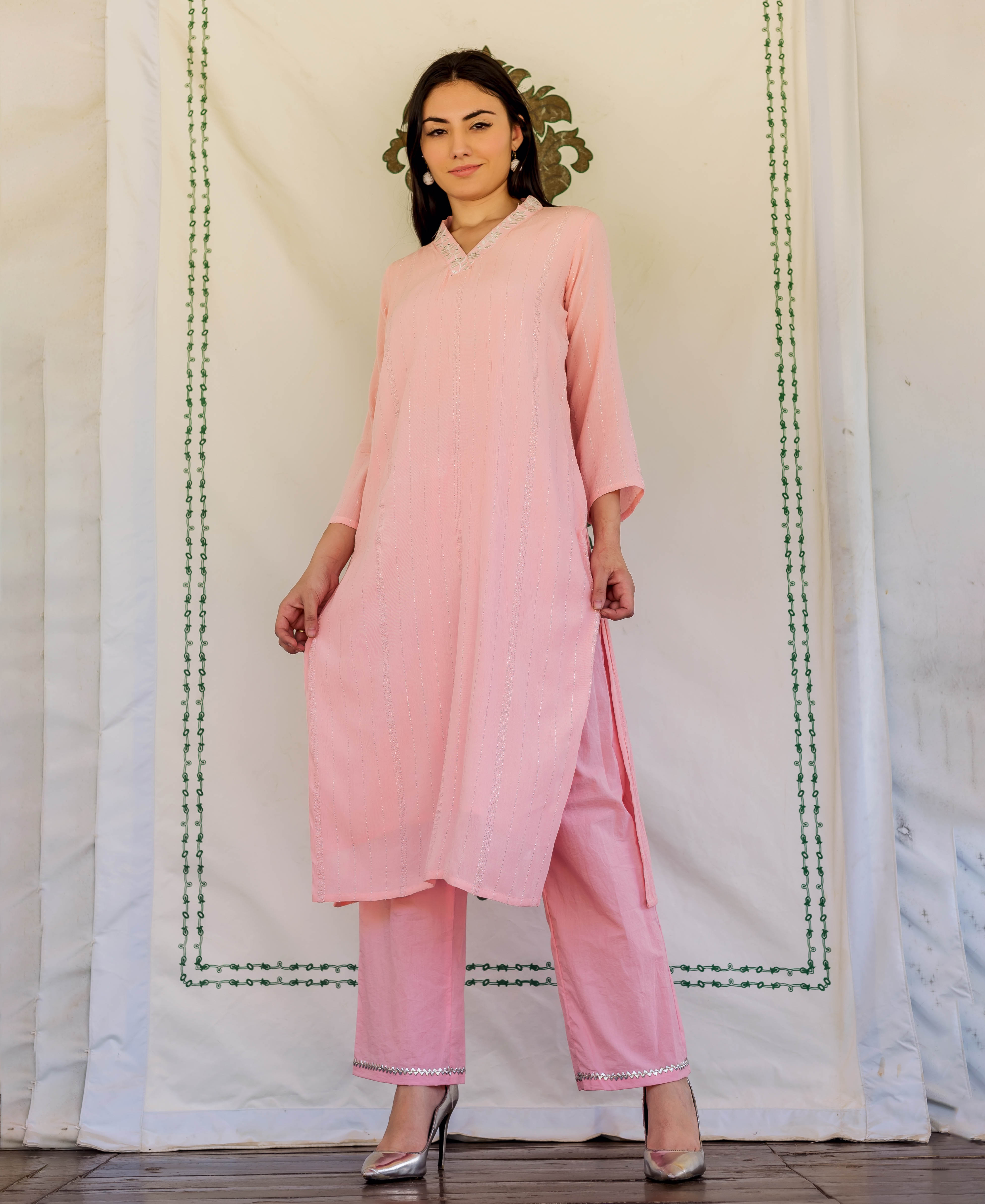 Model in a pink subtly striped kurta set with embroidered neckline and silver trim.