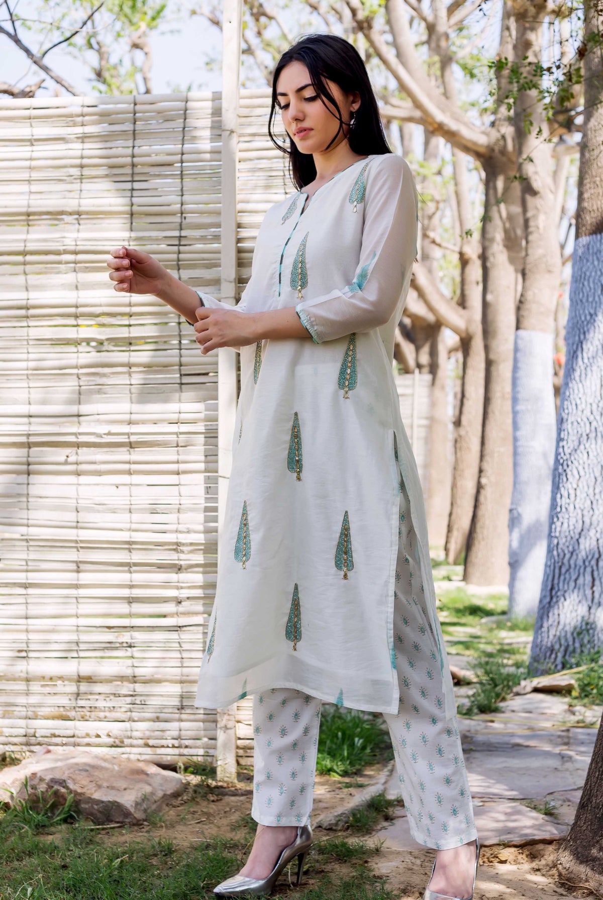 A woman in a white, hand-block-printed kurta with green and gold accents.
