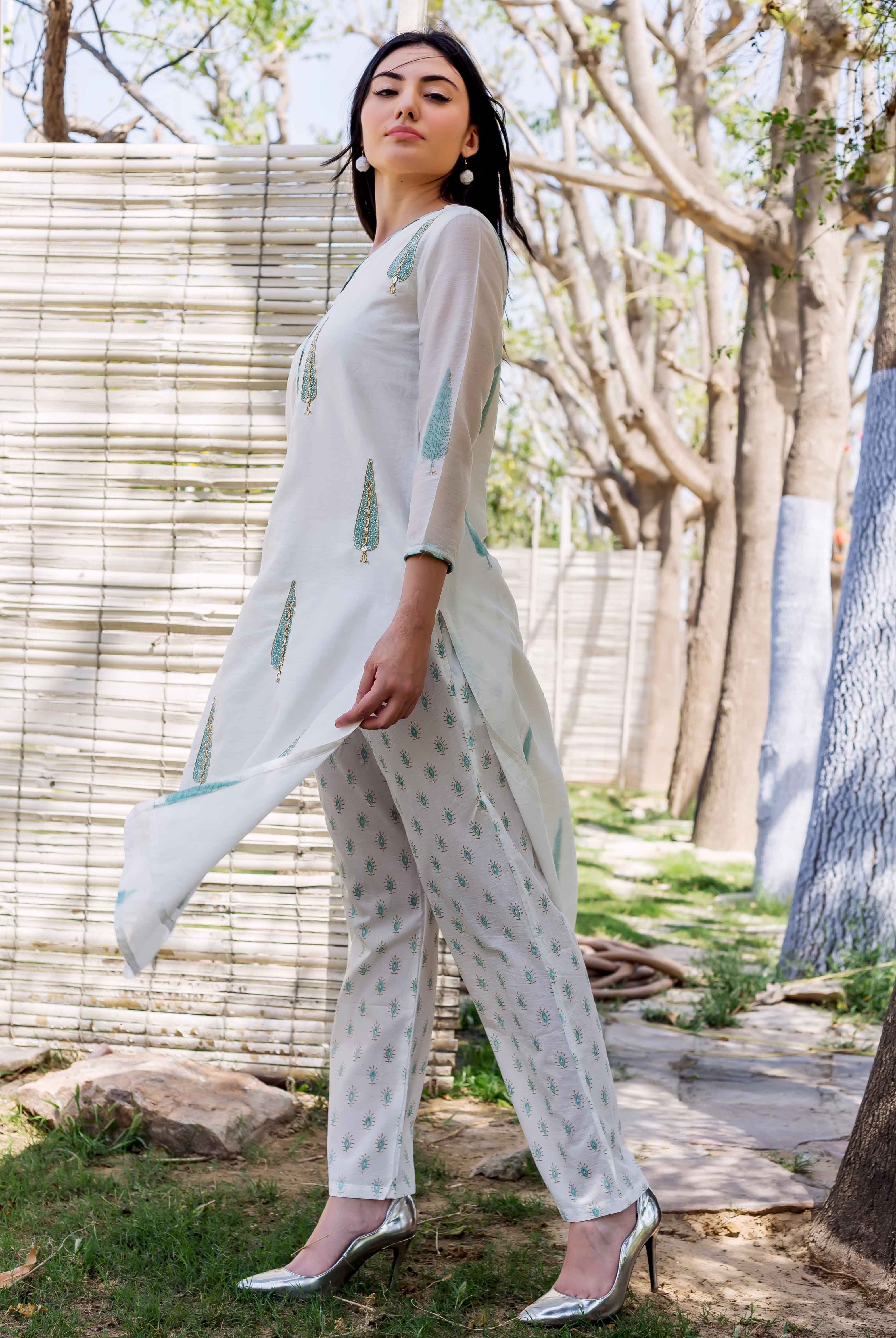 White hand-block-printed straight kurta with blue-green feather-like designs and matching patterned pants on model.