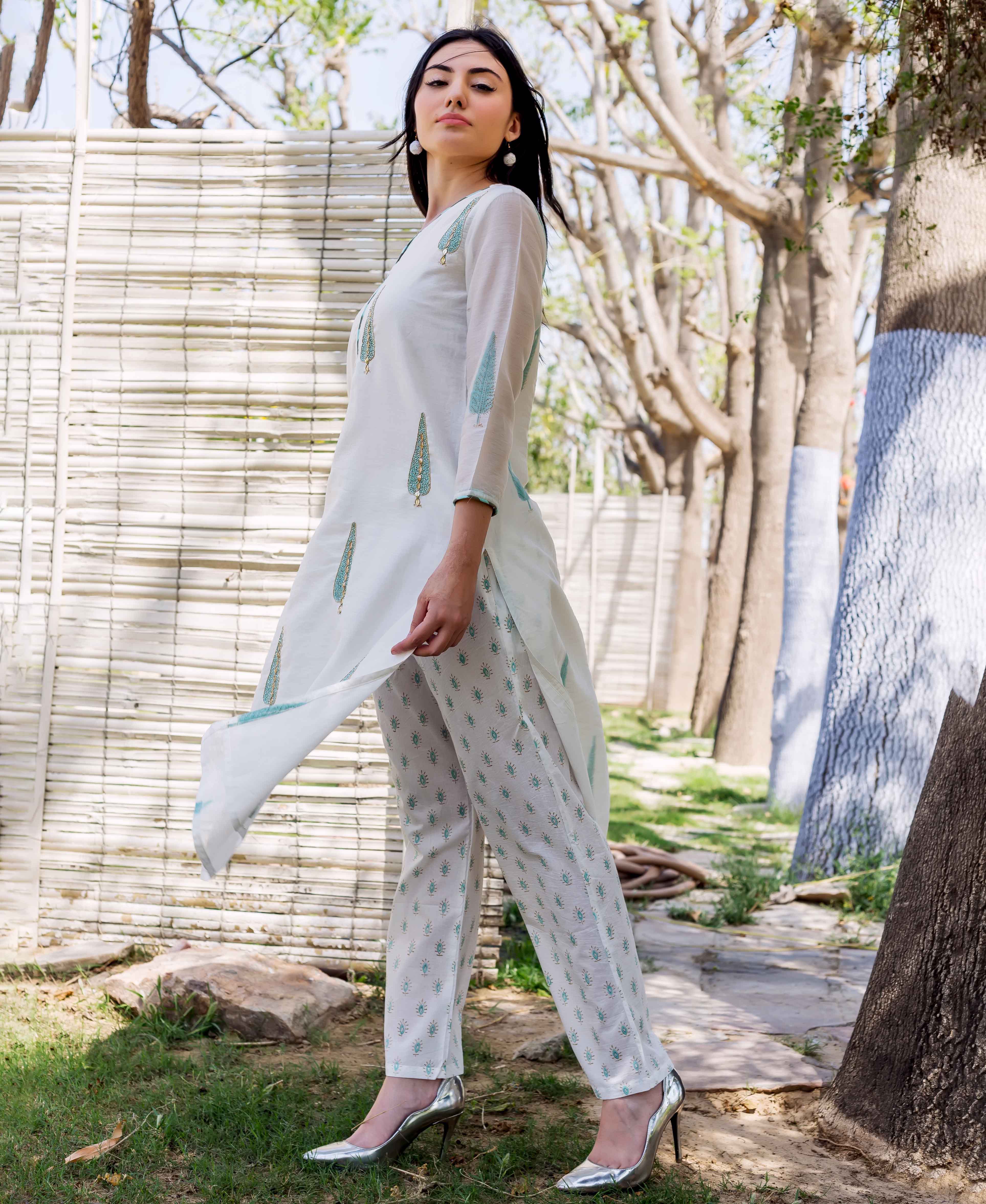 White hand-block-printed straight kurta with blue-green feather-like designs and matching patterned pants on model.