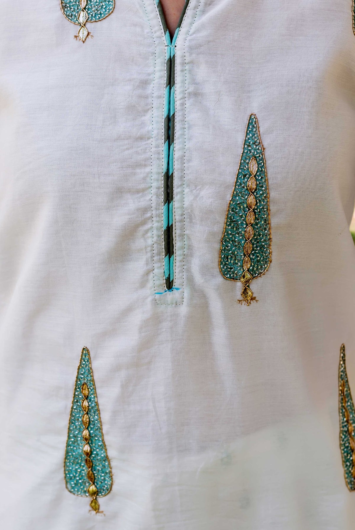 Light grey kurta featuring teal and gold embroidered leaf patterns and a chevron-trimmed placket.