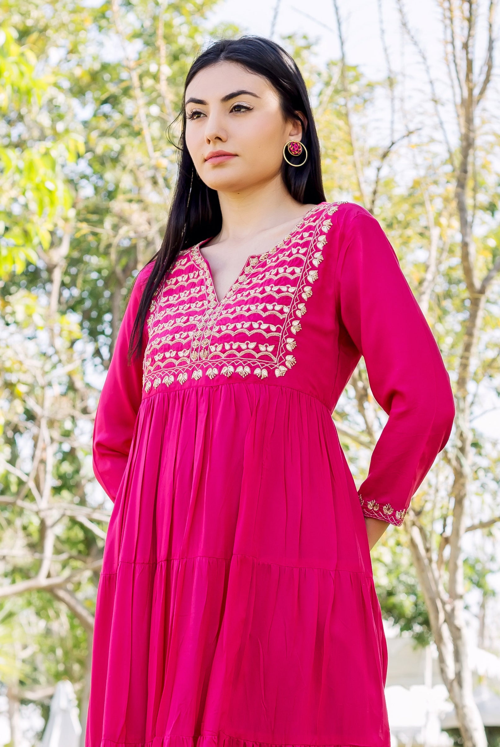 Model in vibrant raspberry red tiered dress with gold embroidered neckline and cuffs.