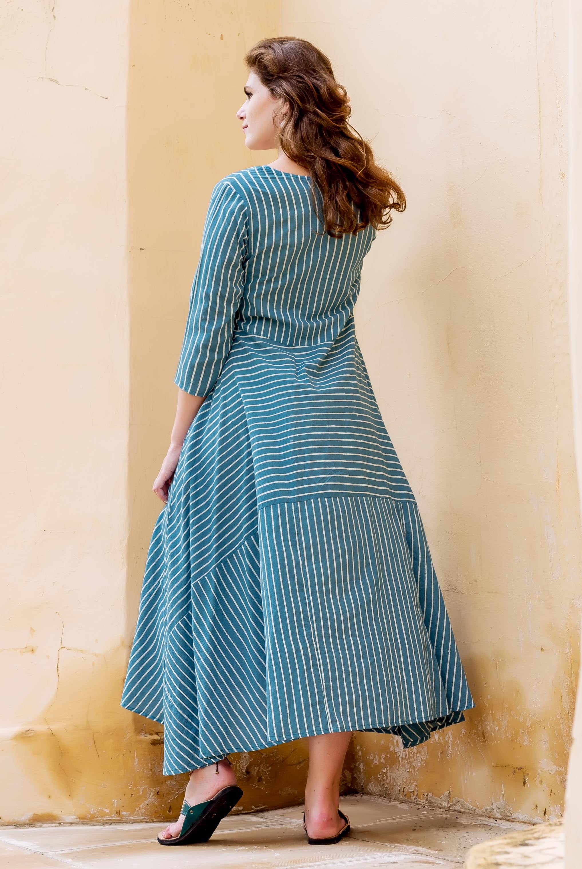 Teal and white striped block printed dress on a model, back view.