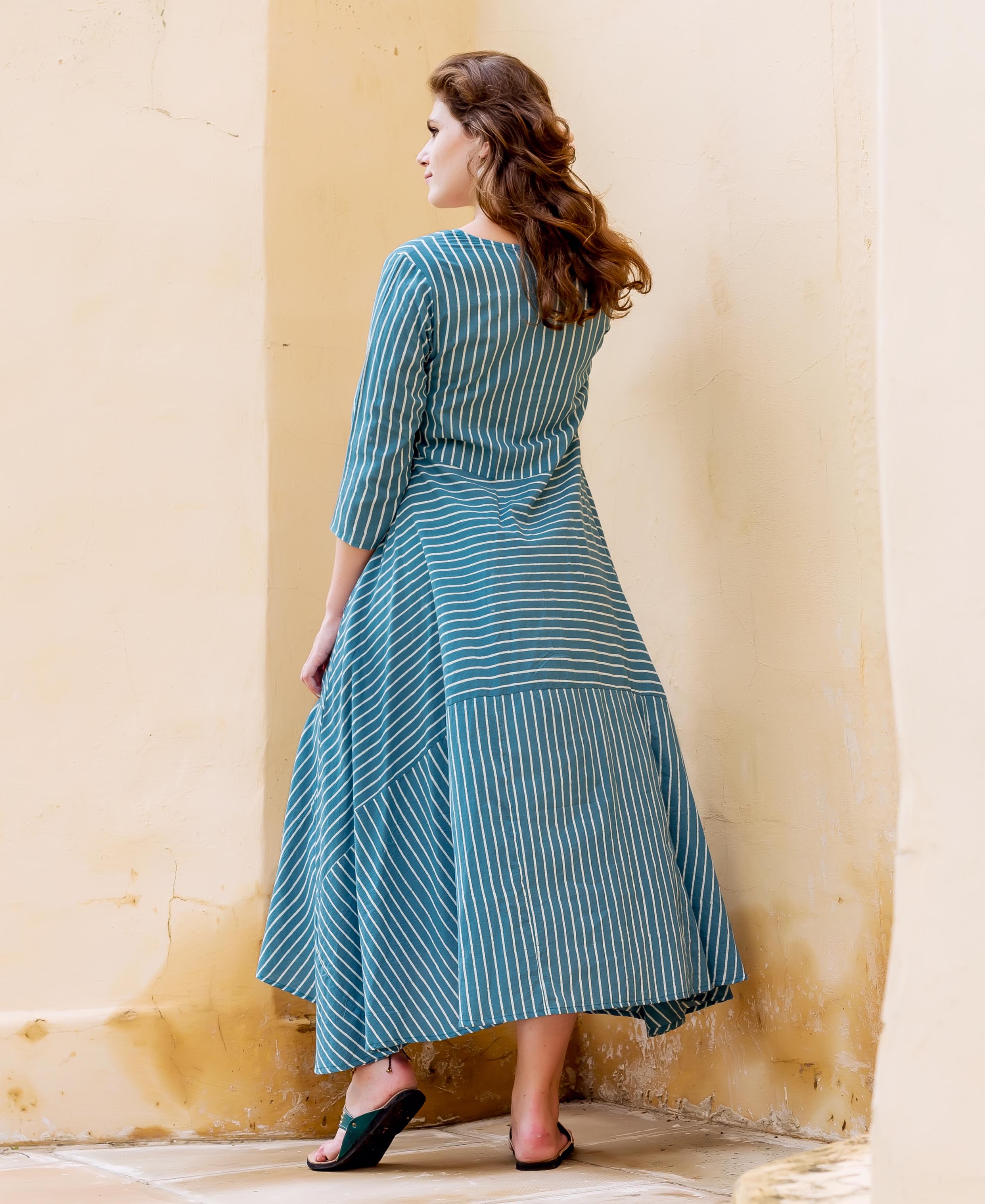 Teal and white striped block printed dress on a model, back view.