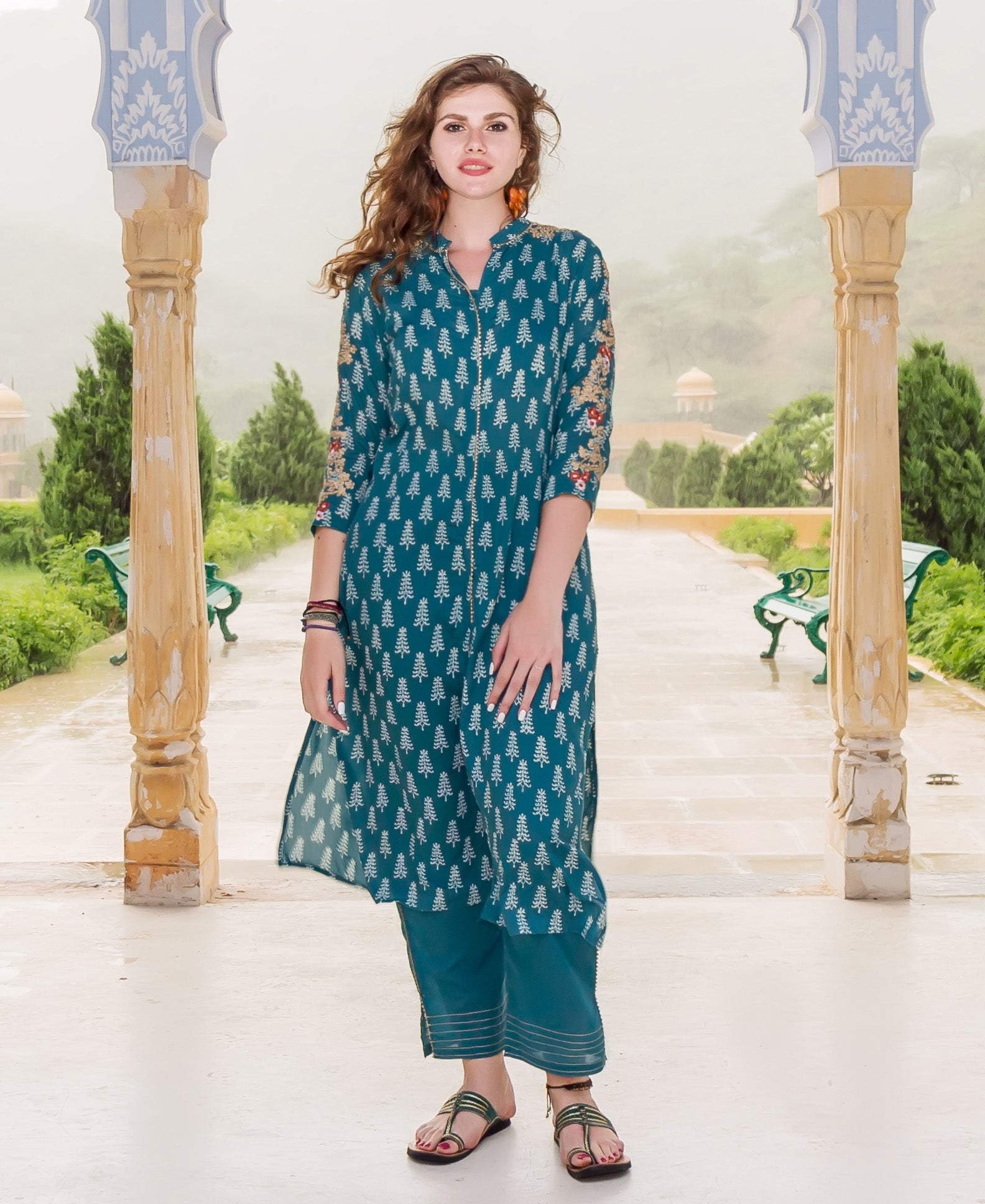 A model wearing a teal kurta with white tree print and floral embroidery on the sleeves.
