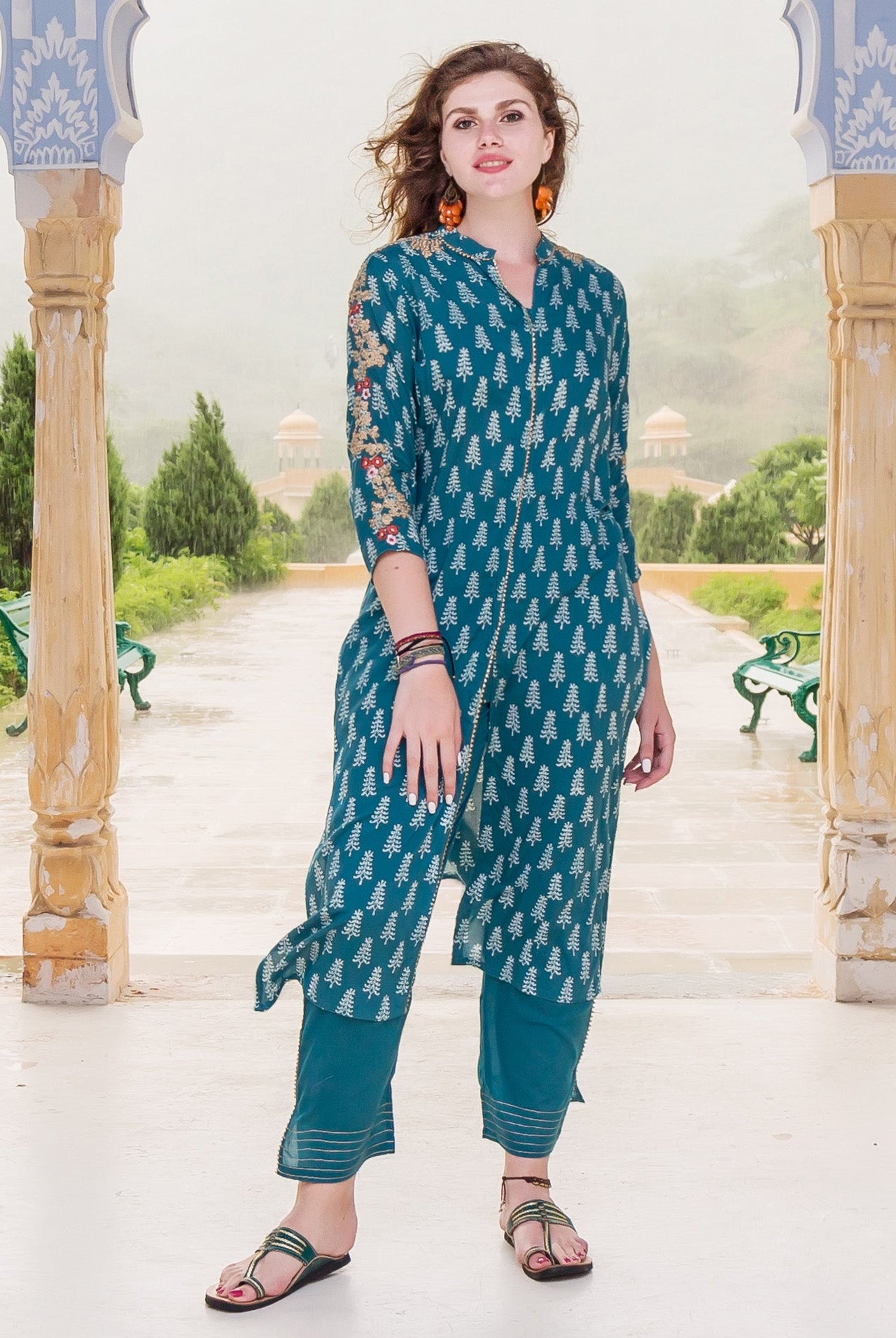 A model wearing a teal kurta with white tree print and embroidered sleeves.
