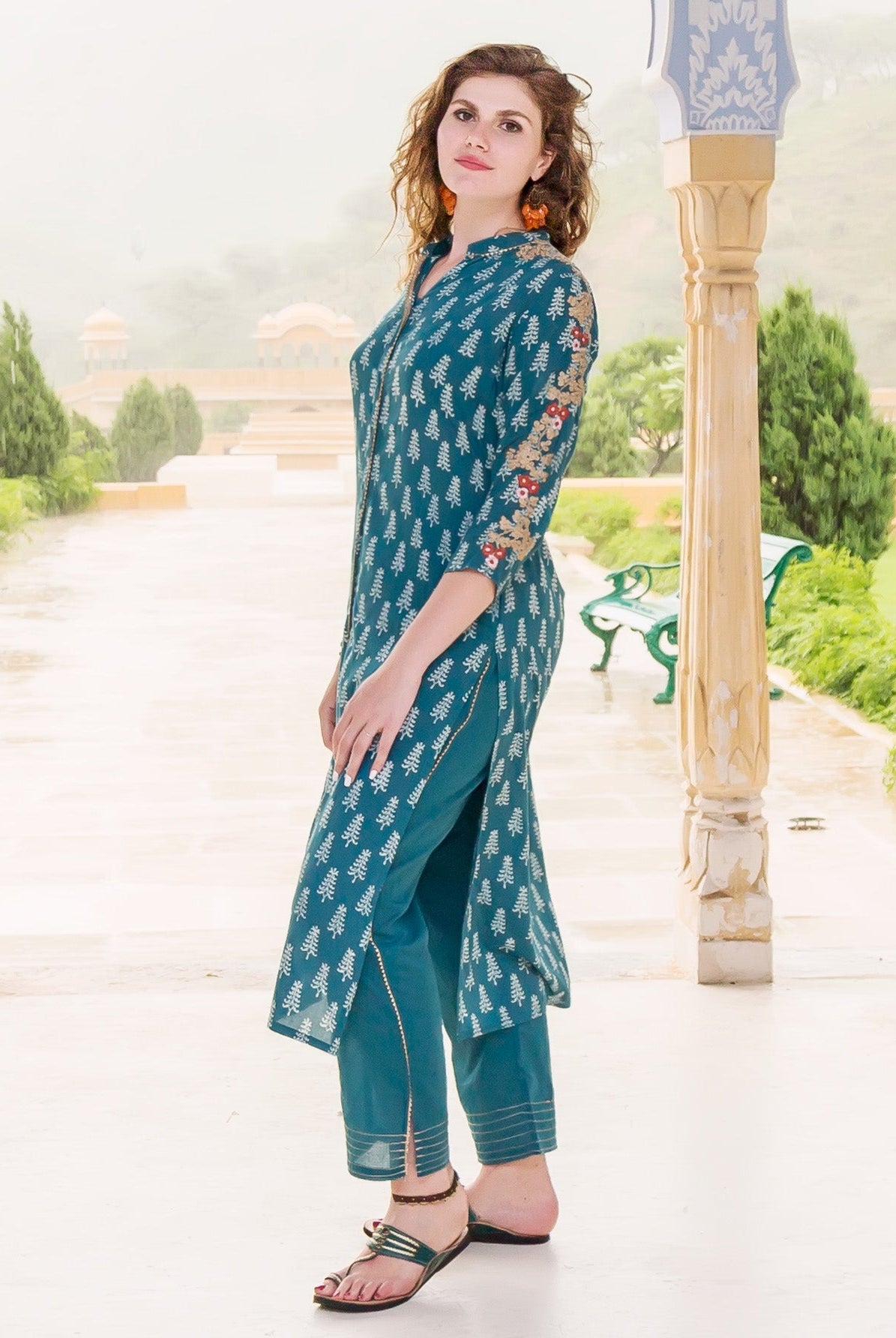 Side view of model in teal embroidered kurta, white hand-block-printed leaf pattern.