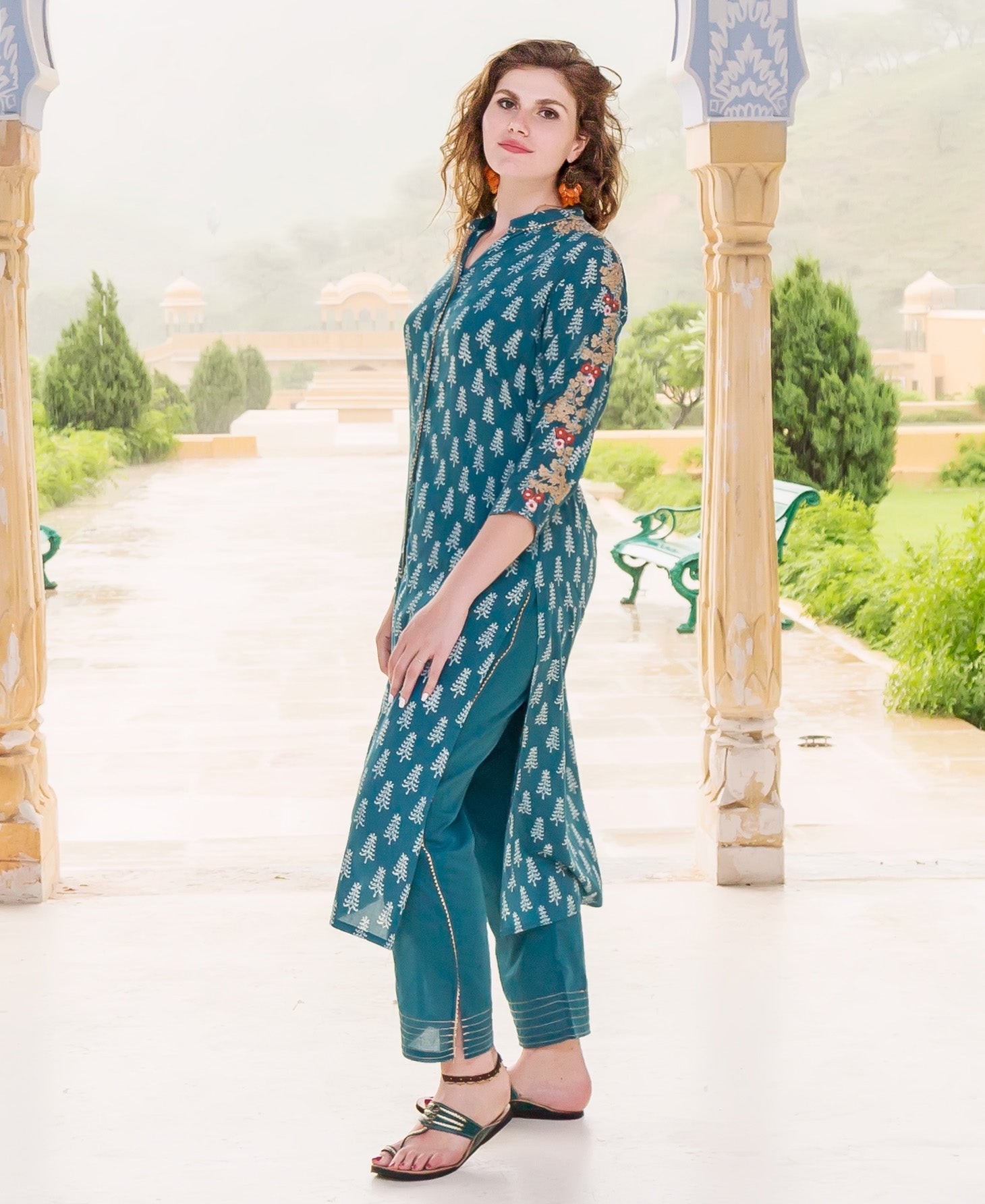 Side view of model in teal embroidered kurta, white hand-block-printed leaf pattern.