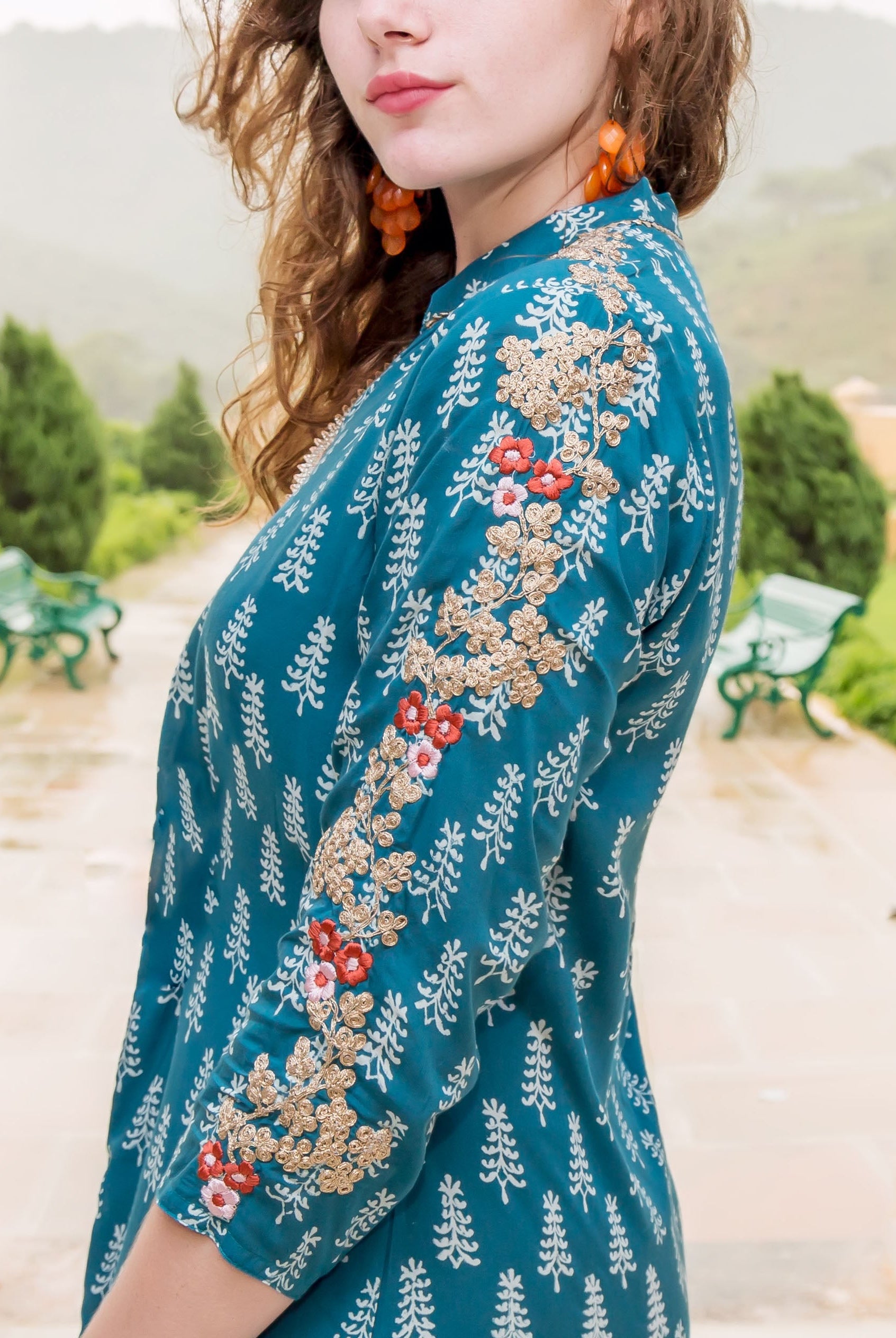 Side view of model wearing a teal hand-block-printed kurta with gold and red embroidery.