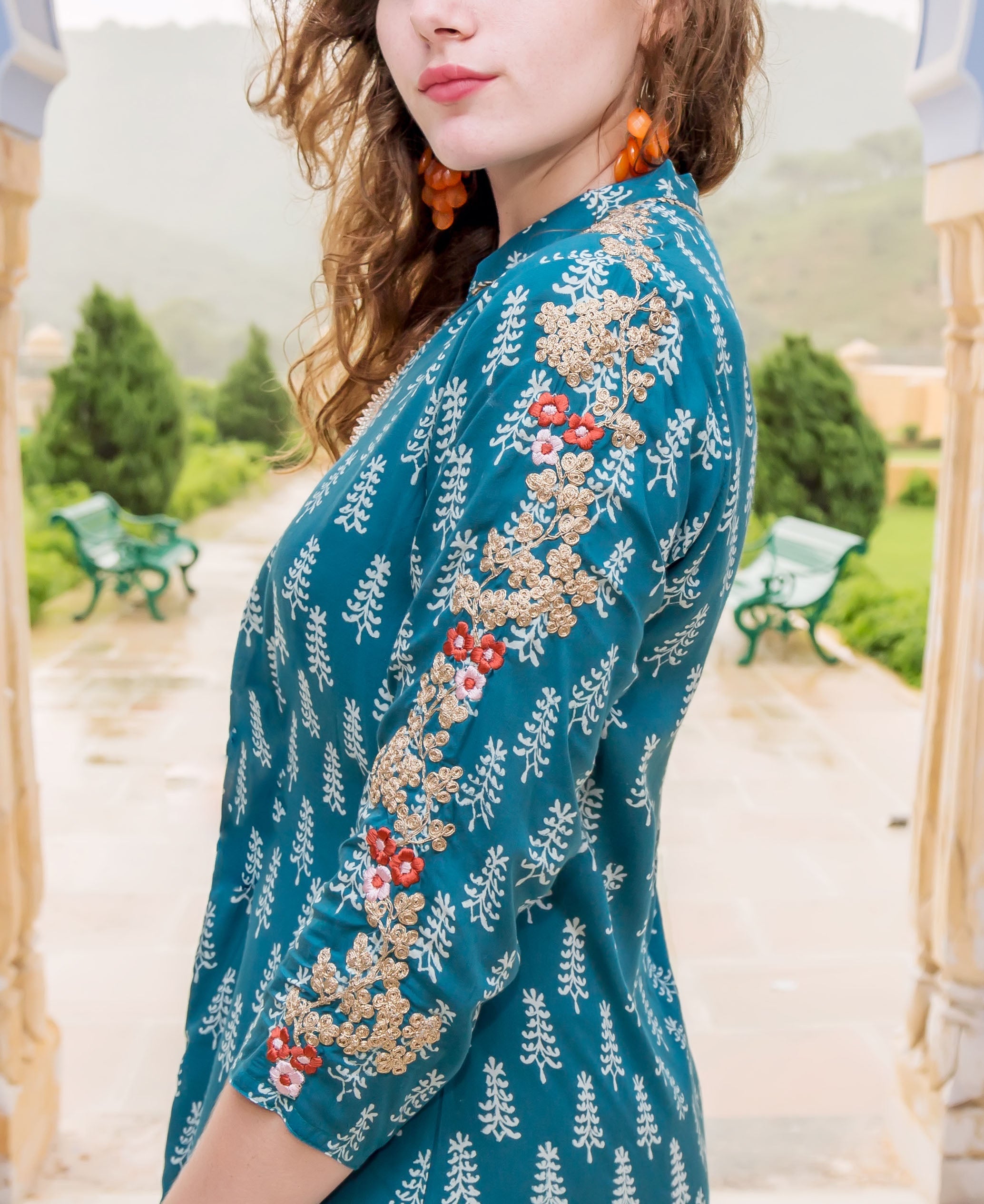 Side view of model wearing a teal hand-block-printed kurta with gold and red embroidery.