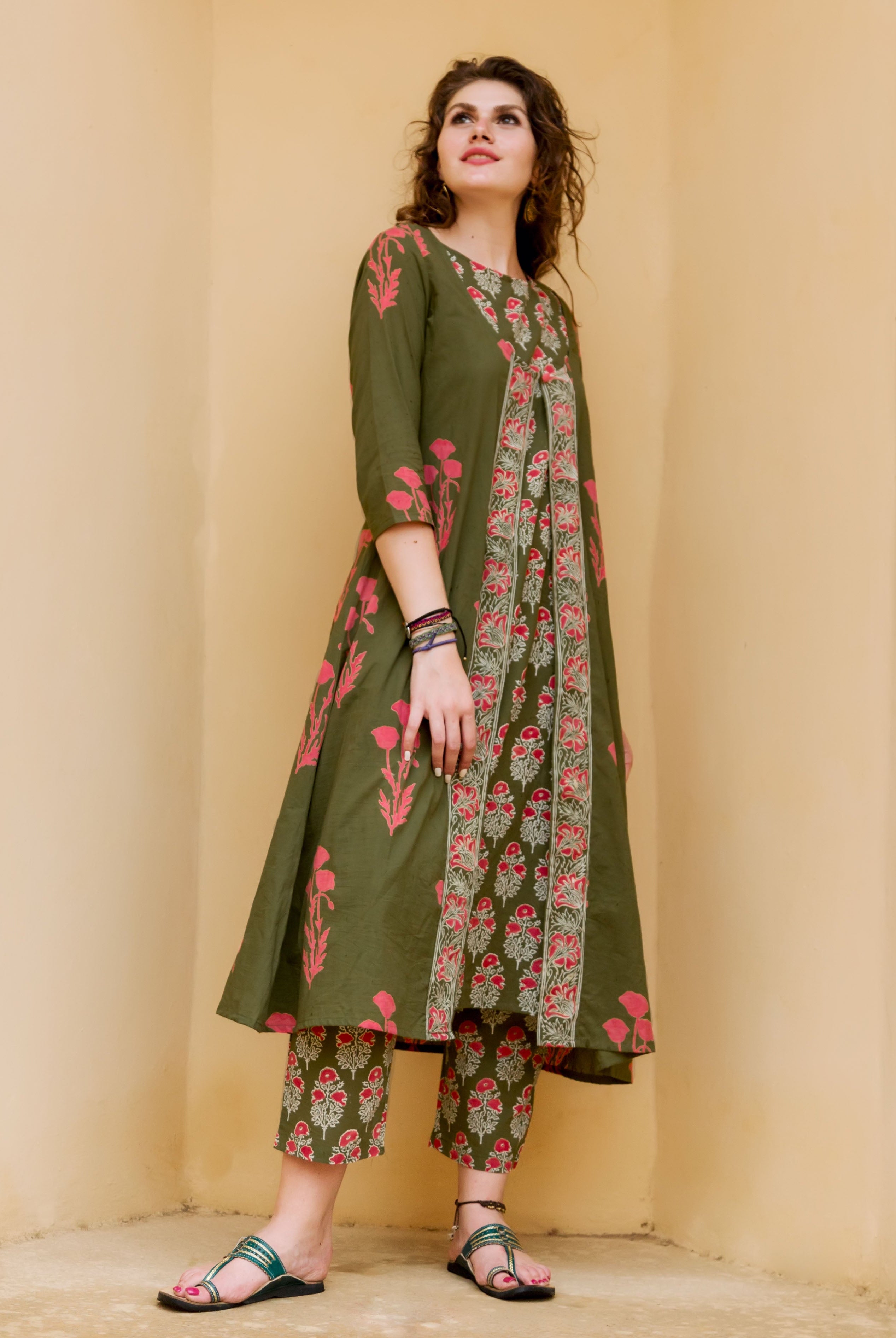 Woman wearing an olive green kurta and cropped pants featuring red hand-block-printed ethnic patterns.
