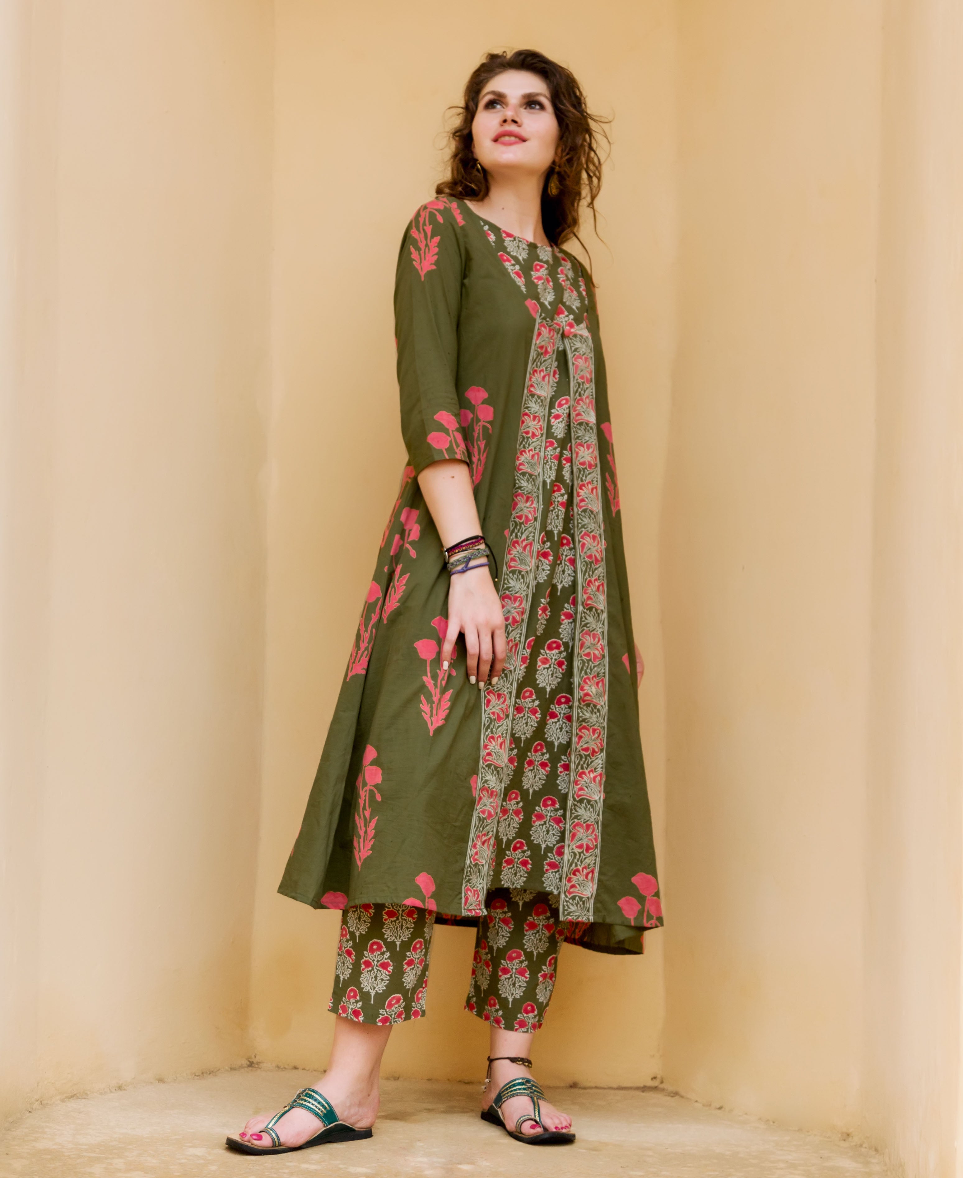 Woman wearing an olive green kurta and cropped pants featuring red hand-block-printed ethnic patterns.