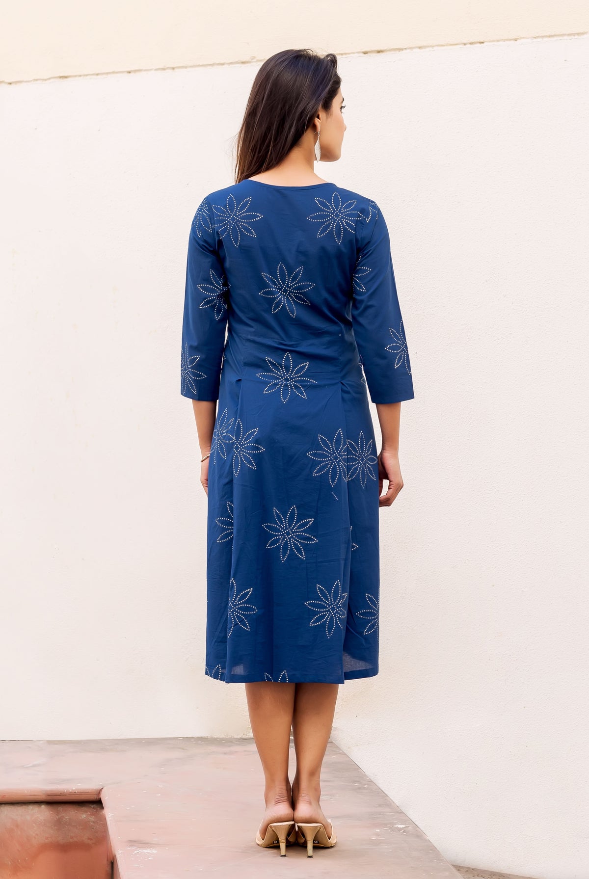 Back view model in indigo hand-block-printed dress with white dotted floral patterns.
